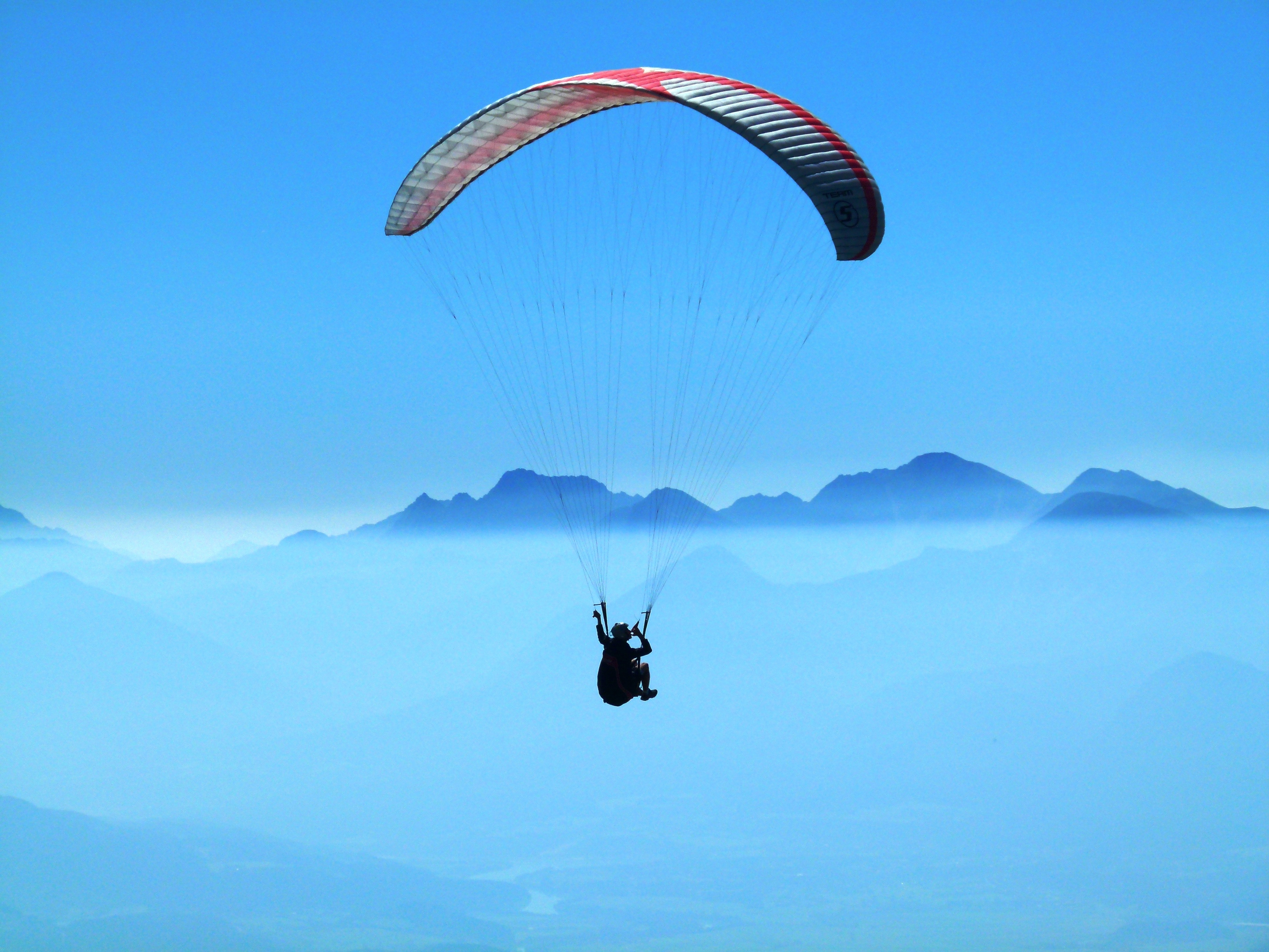 Person doing paragliding above clouds during daytime photo