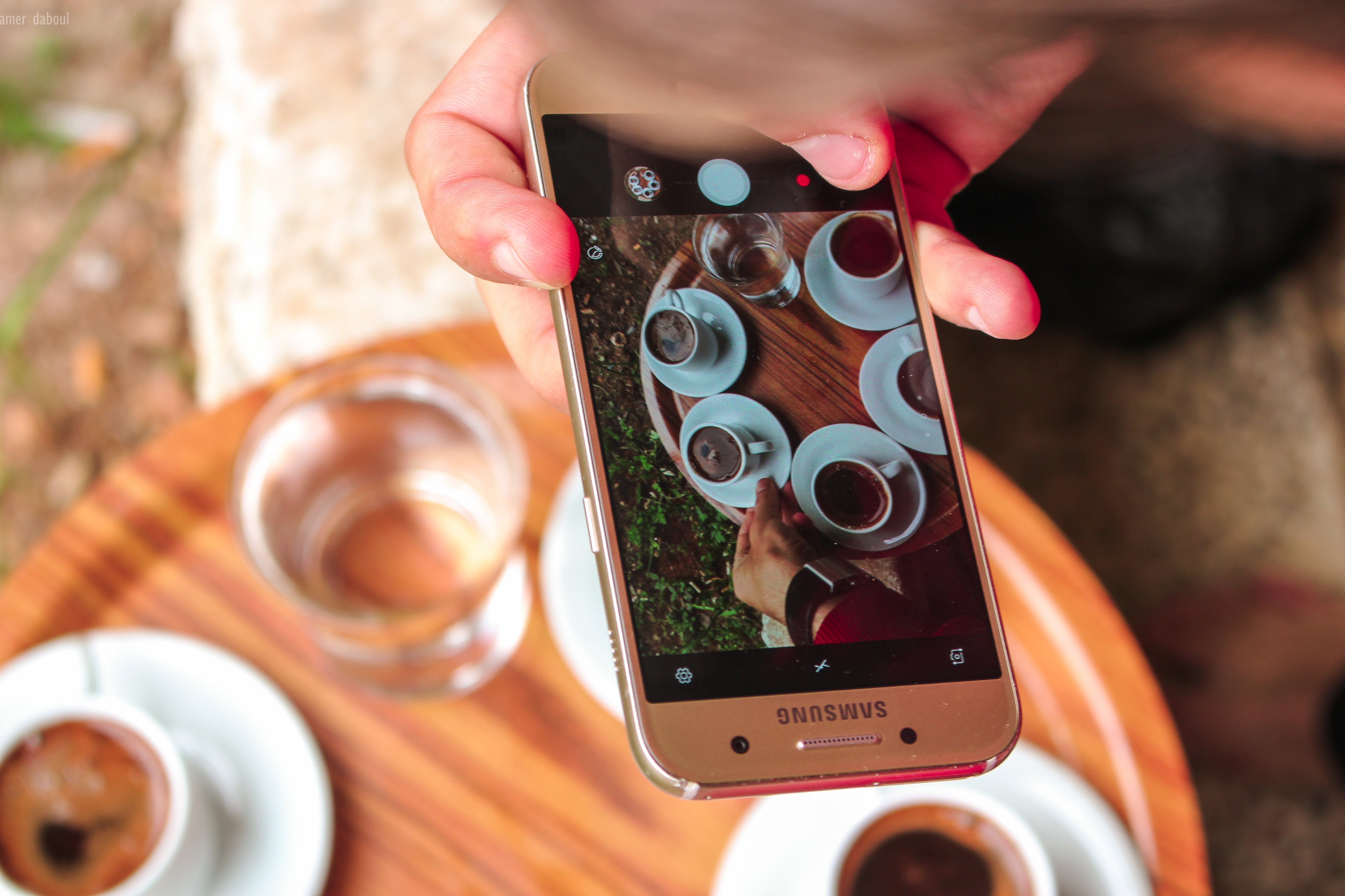 Person holding a samsung galaxy smartphone taking a picture on their coffees photo