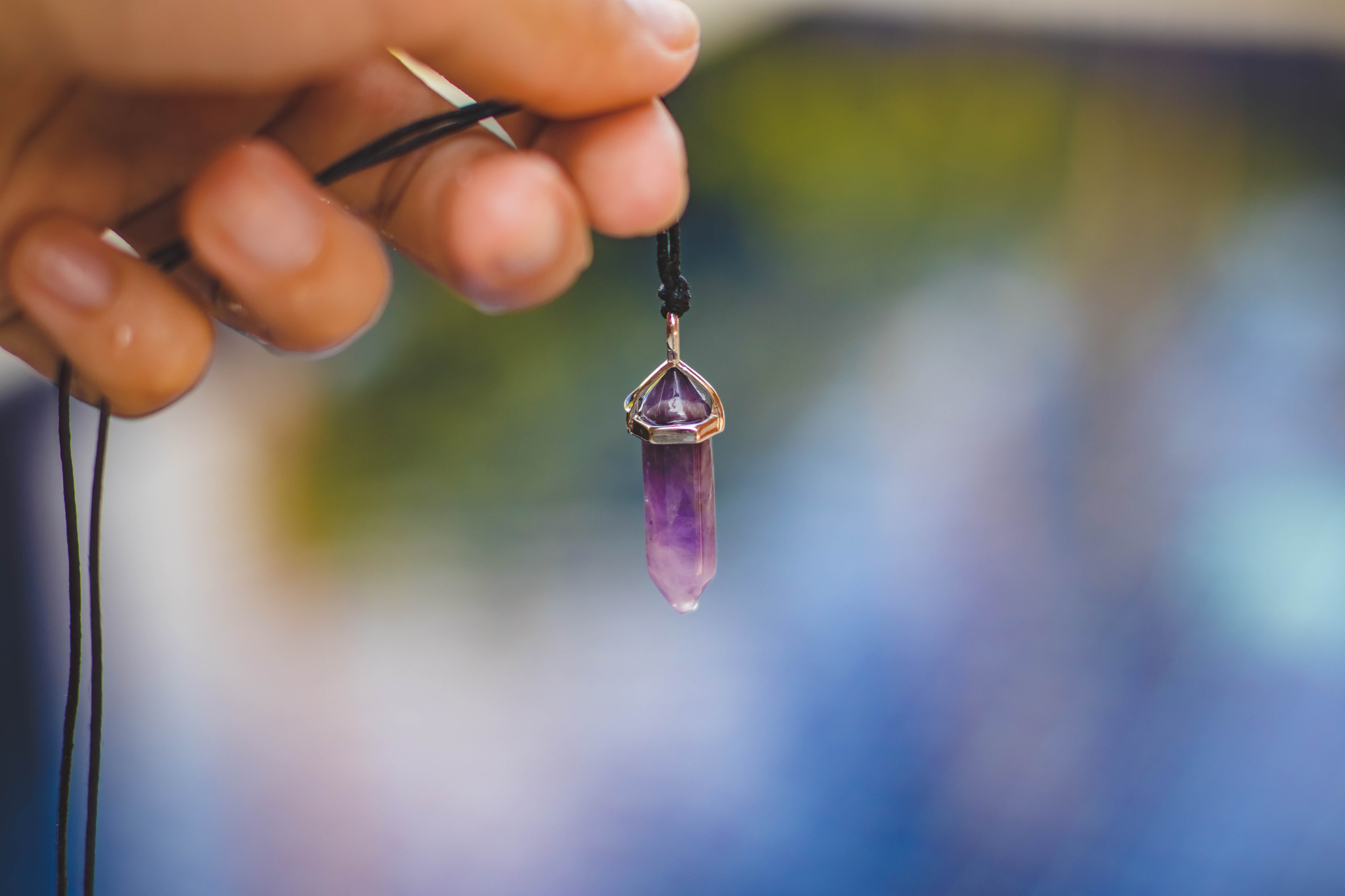 Person holding black necklace with purple stone pendant photo