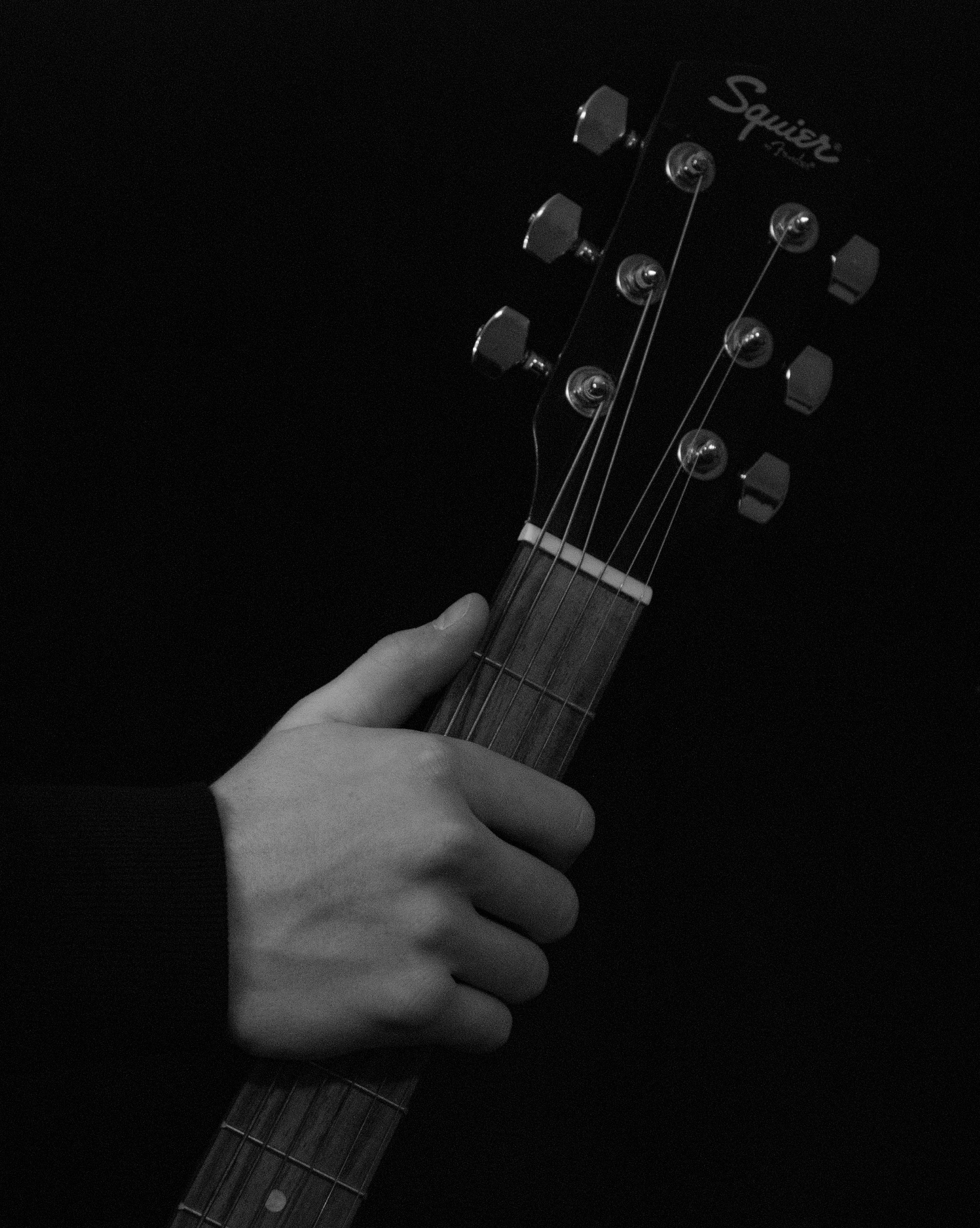 Person holding black squier fender guitar photo