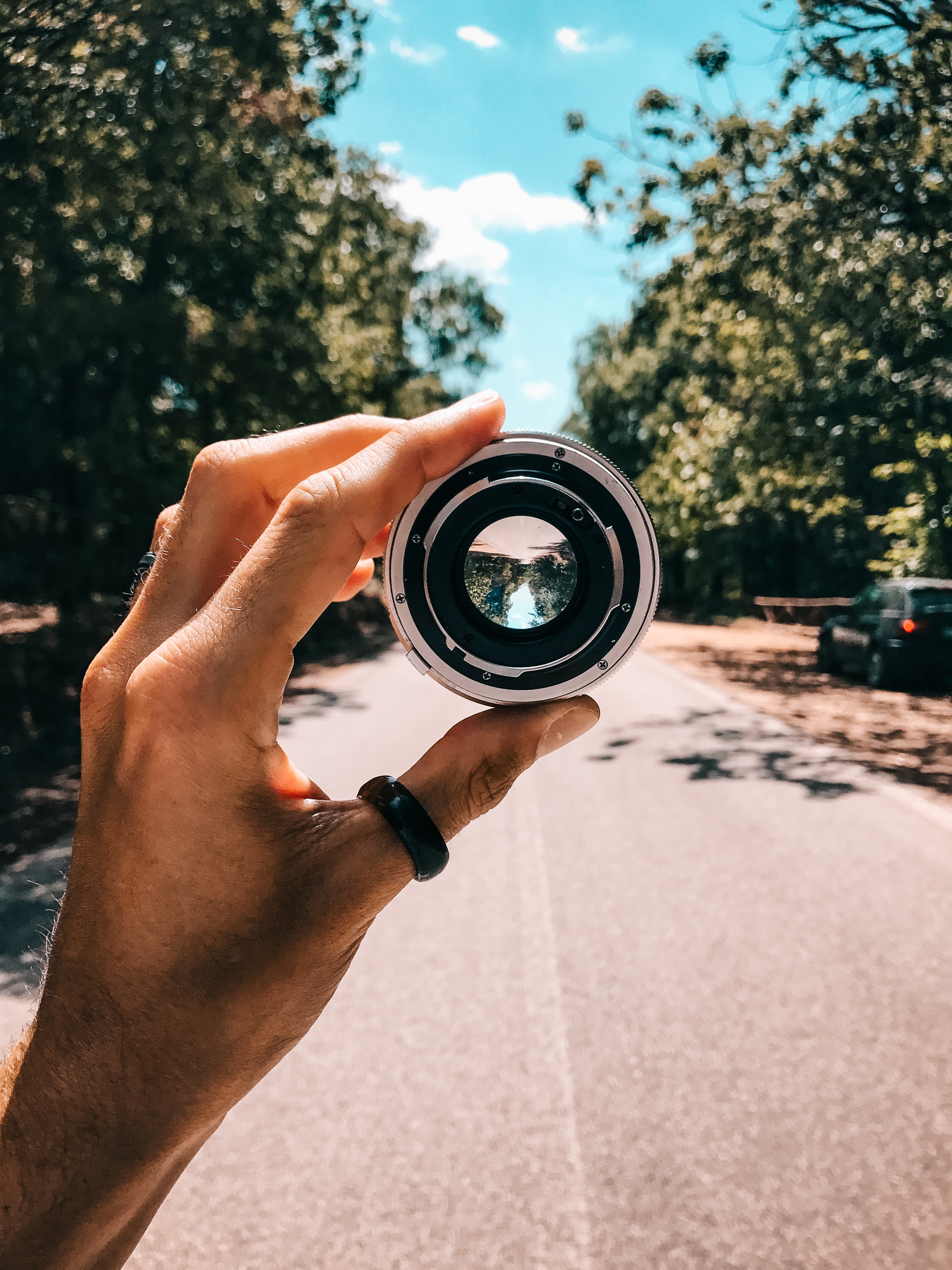 Person holding camera lens in the middle of street under blue sky photo