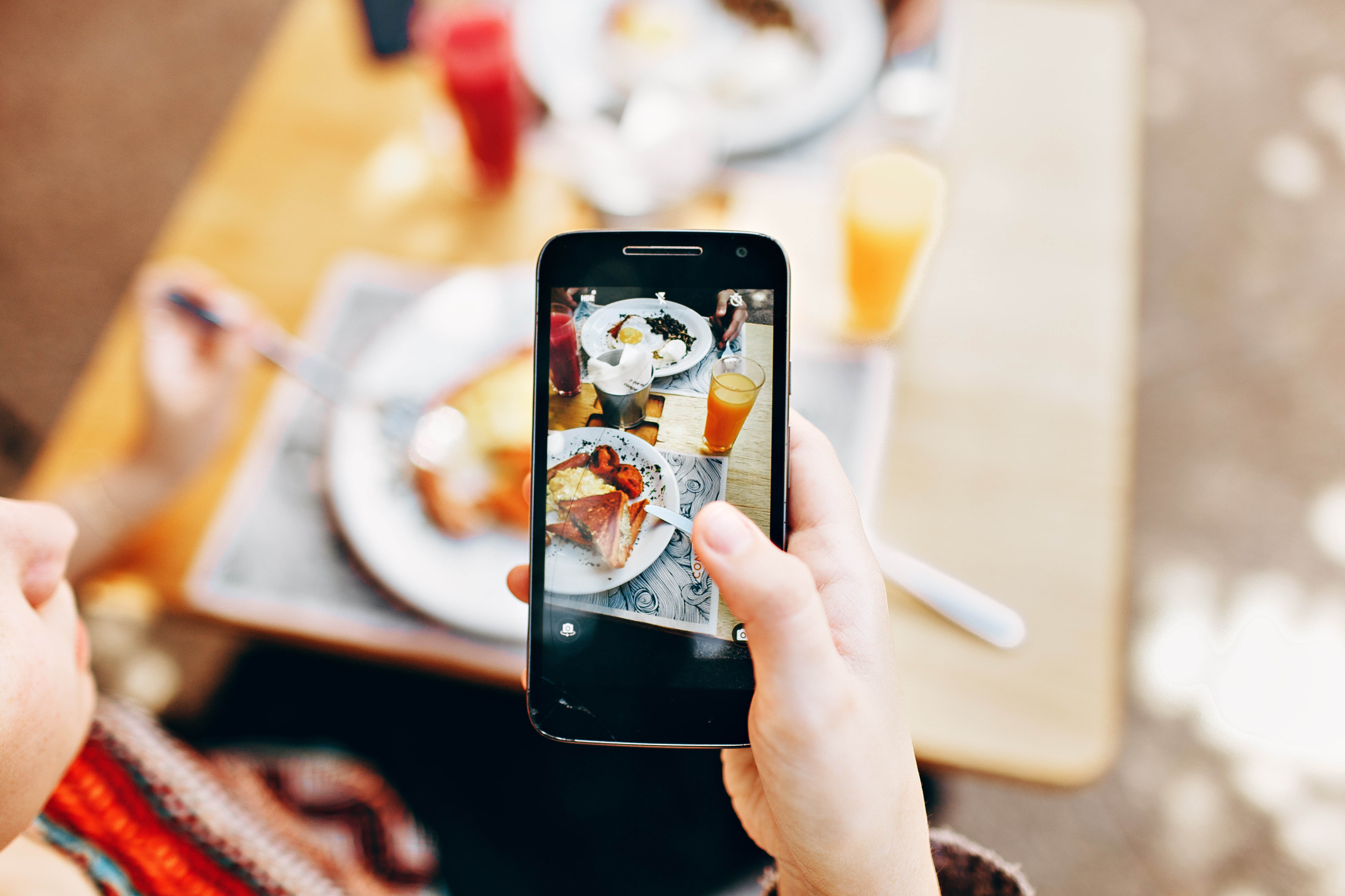 Person holding phone taking picture of served food photo