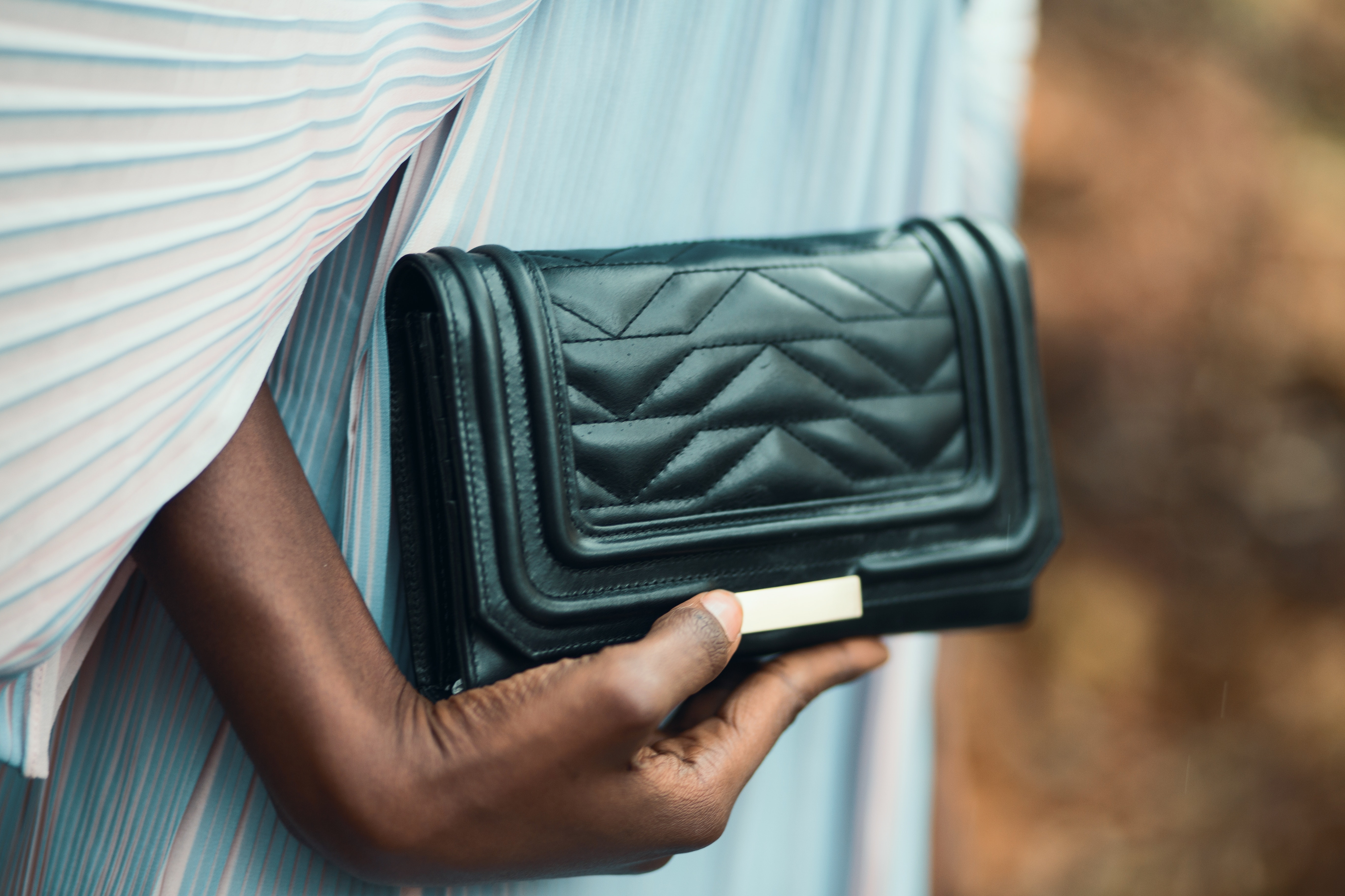 Person holding quilted black leather clutch bag photo