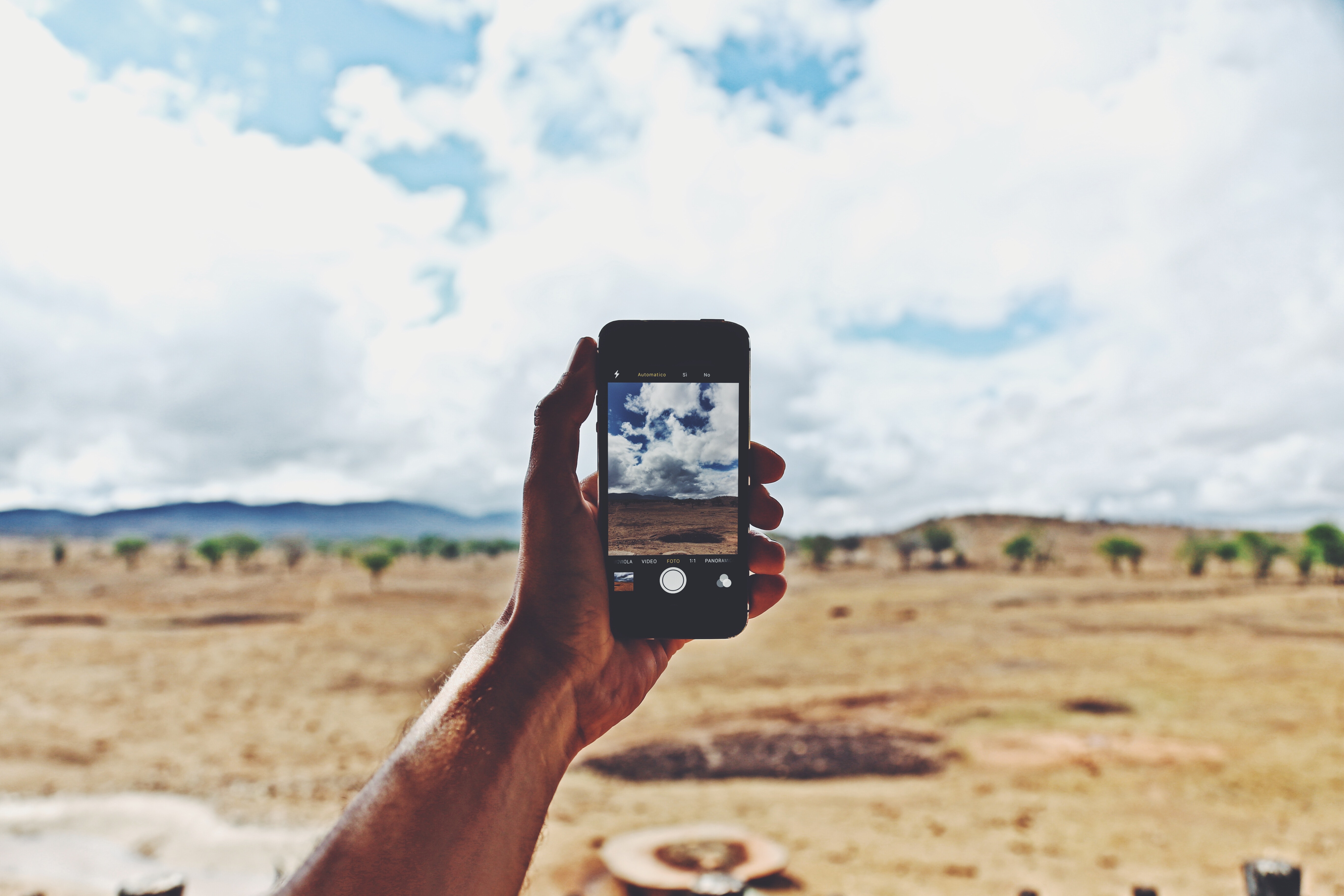 Person holding smartphone showing cloudy sky photo