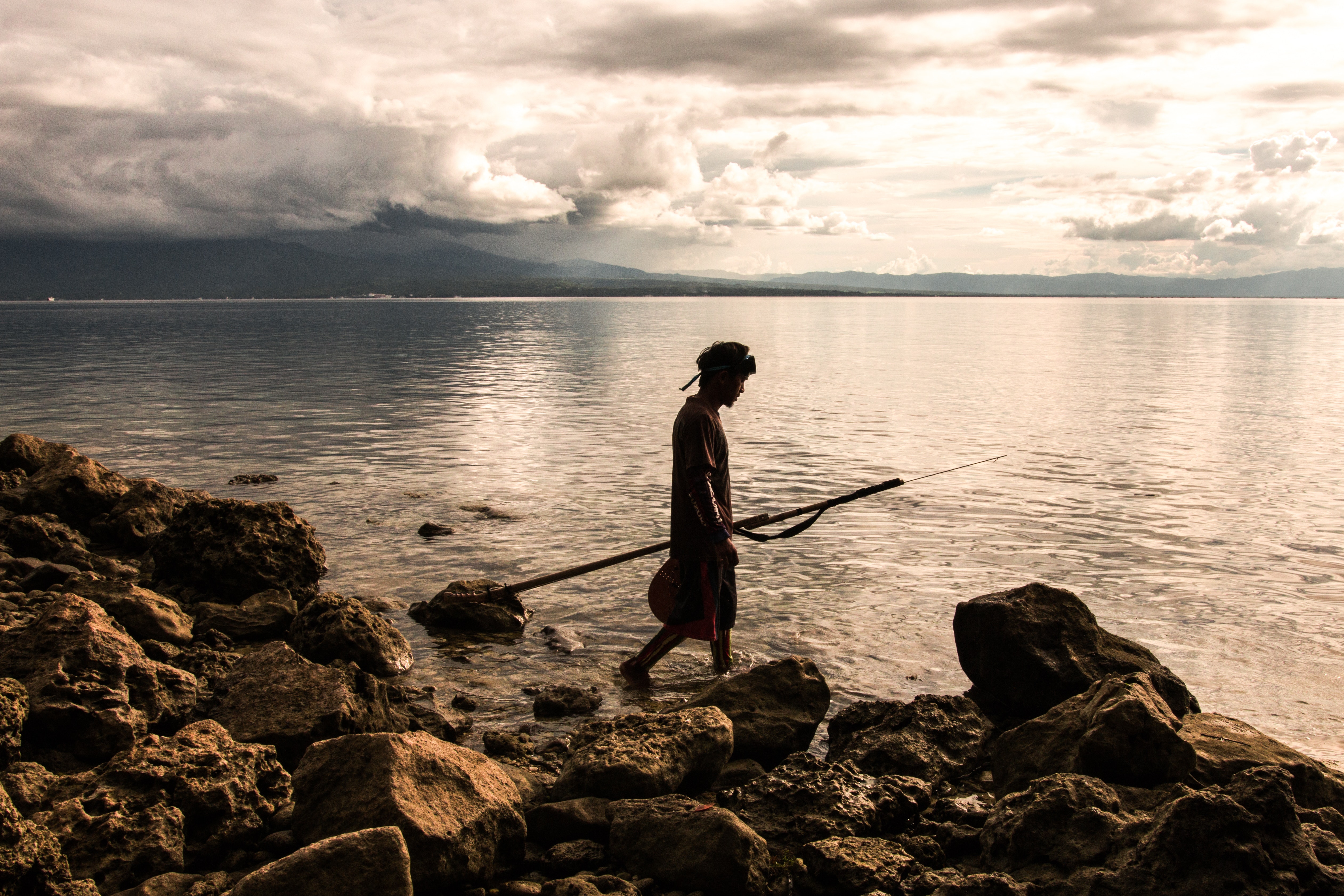 Person holding spear beside body of water photo