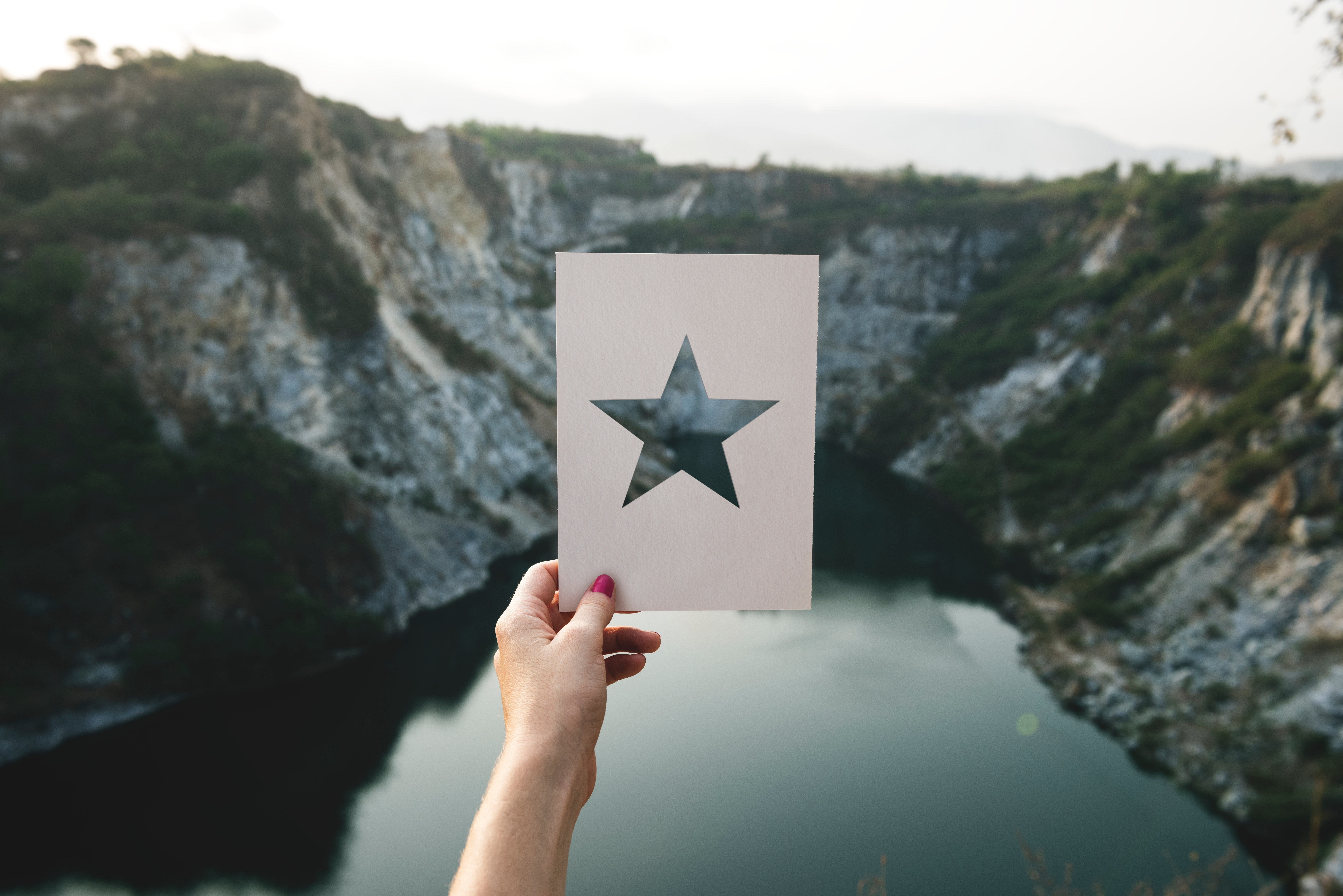 Person holding star cutout paper facing mountain photo