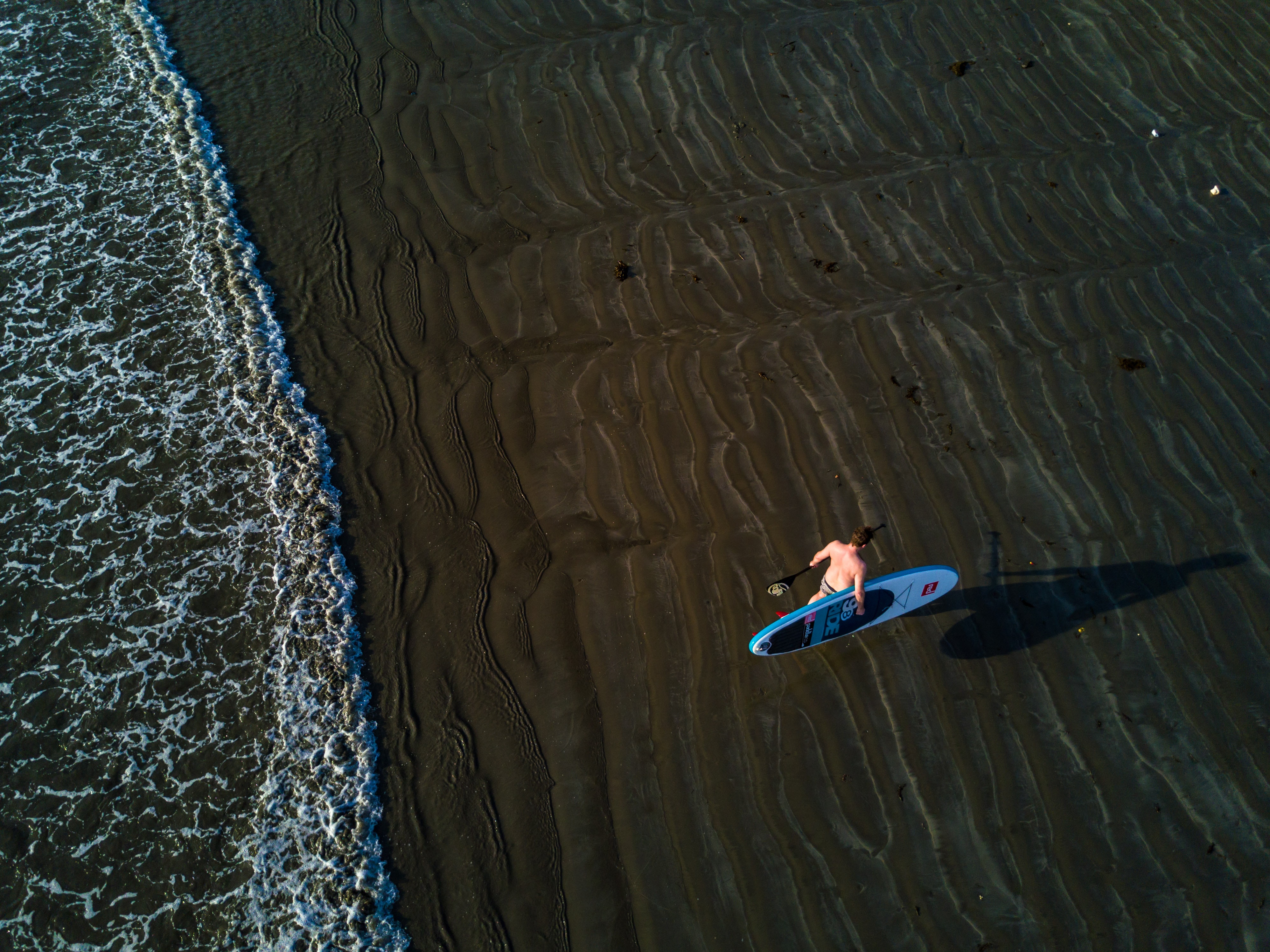 Person holding surfboard near seashore photo