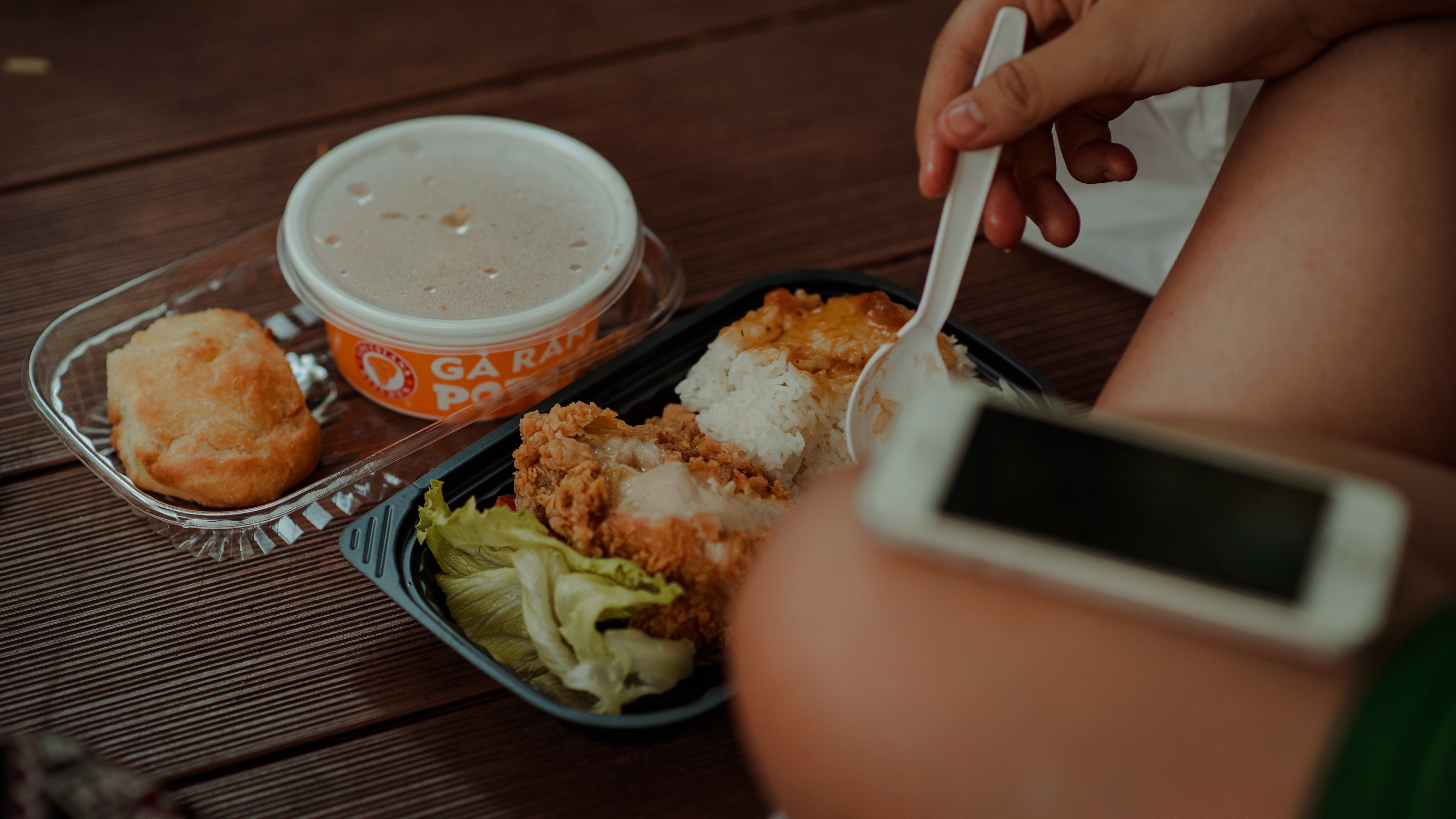 Person holding white disposable spoon eating fried chicken photo