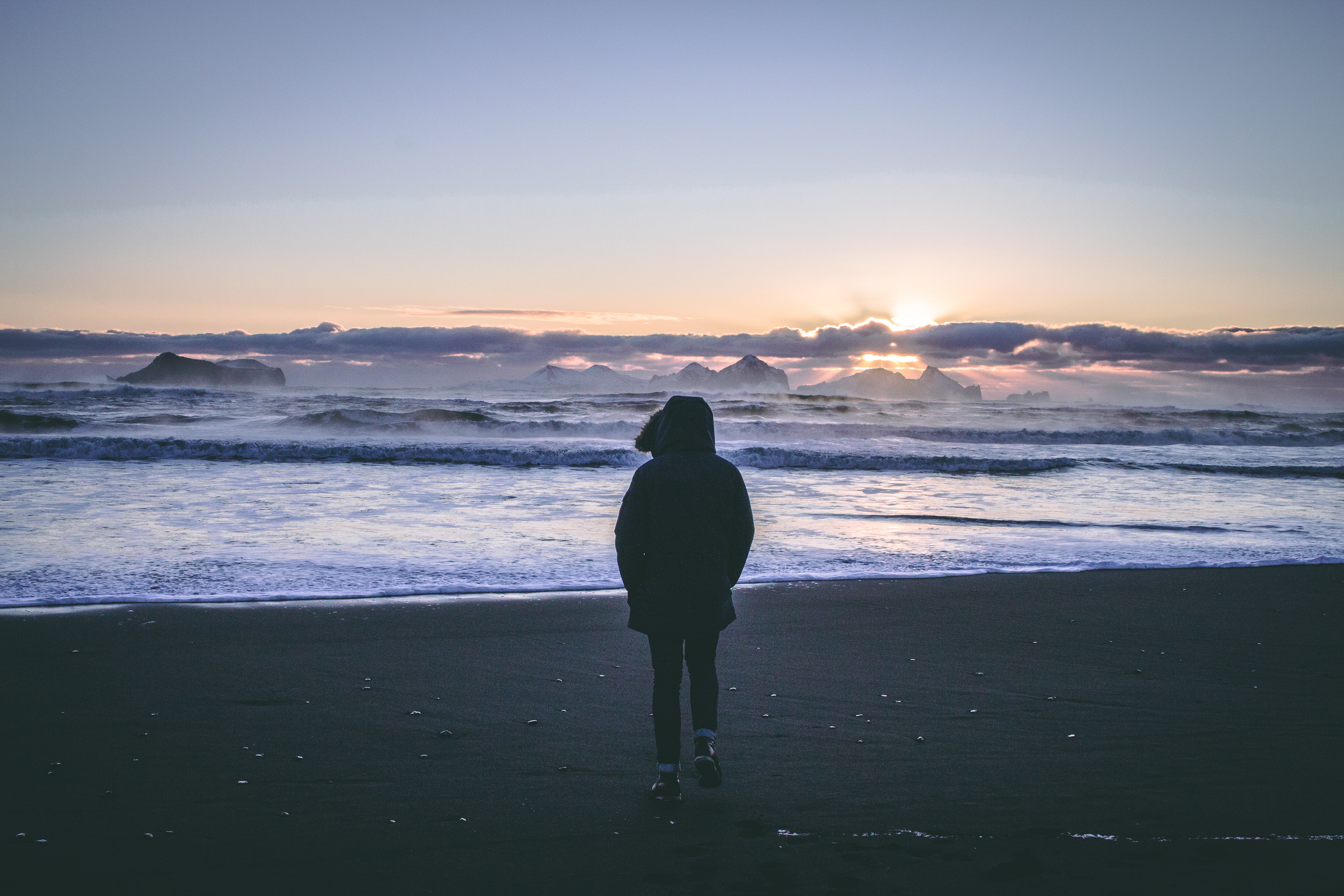 Person in black hoodie near seashore during sunset photo