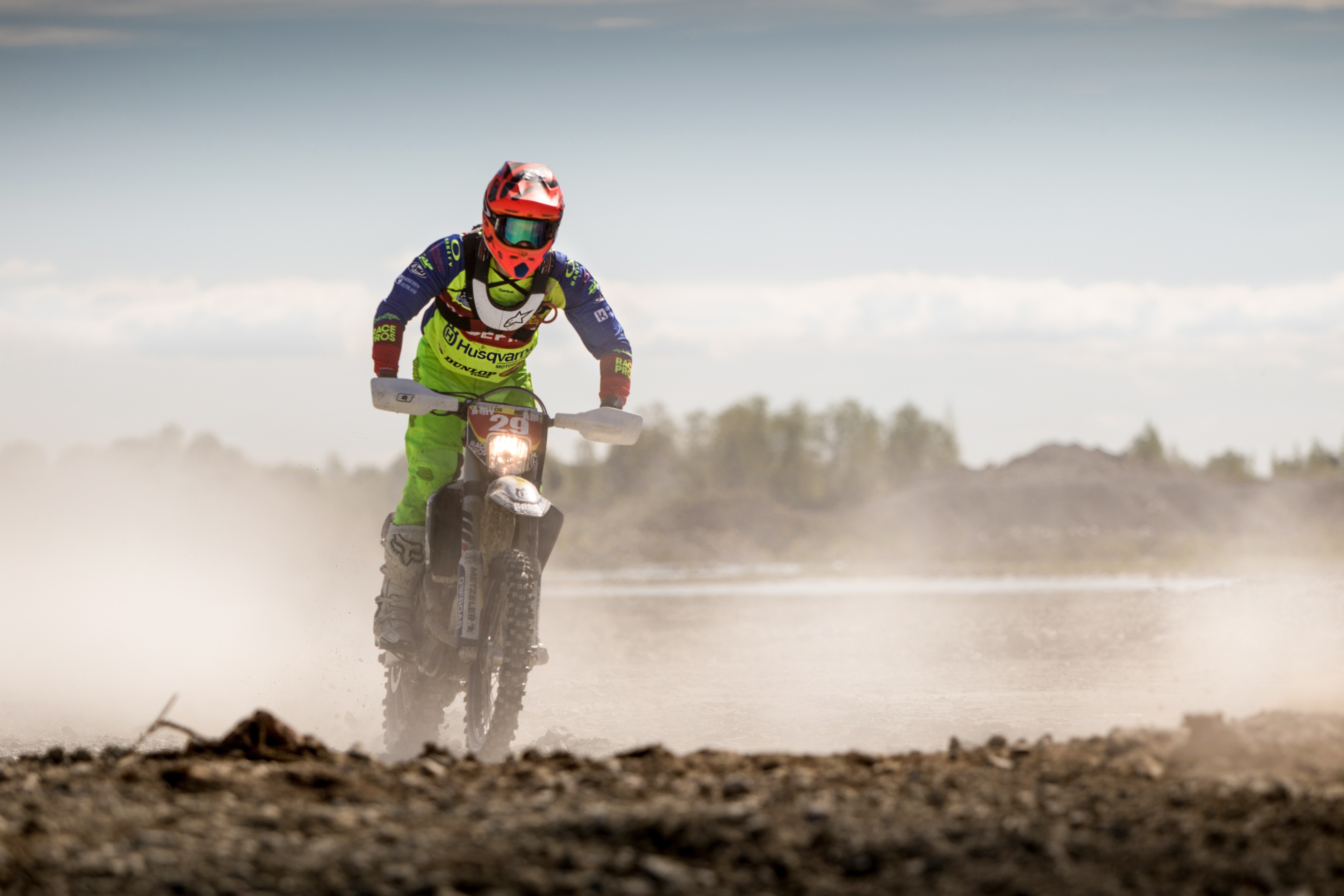 Person in green motocross gear riding a dirt bike photo
