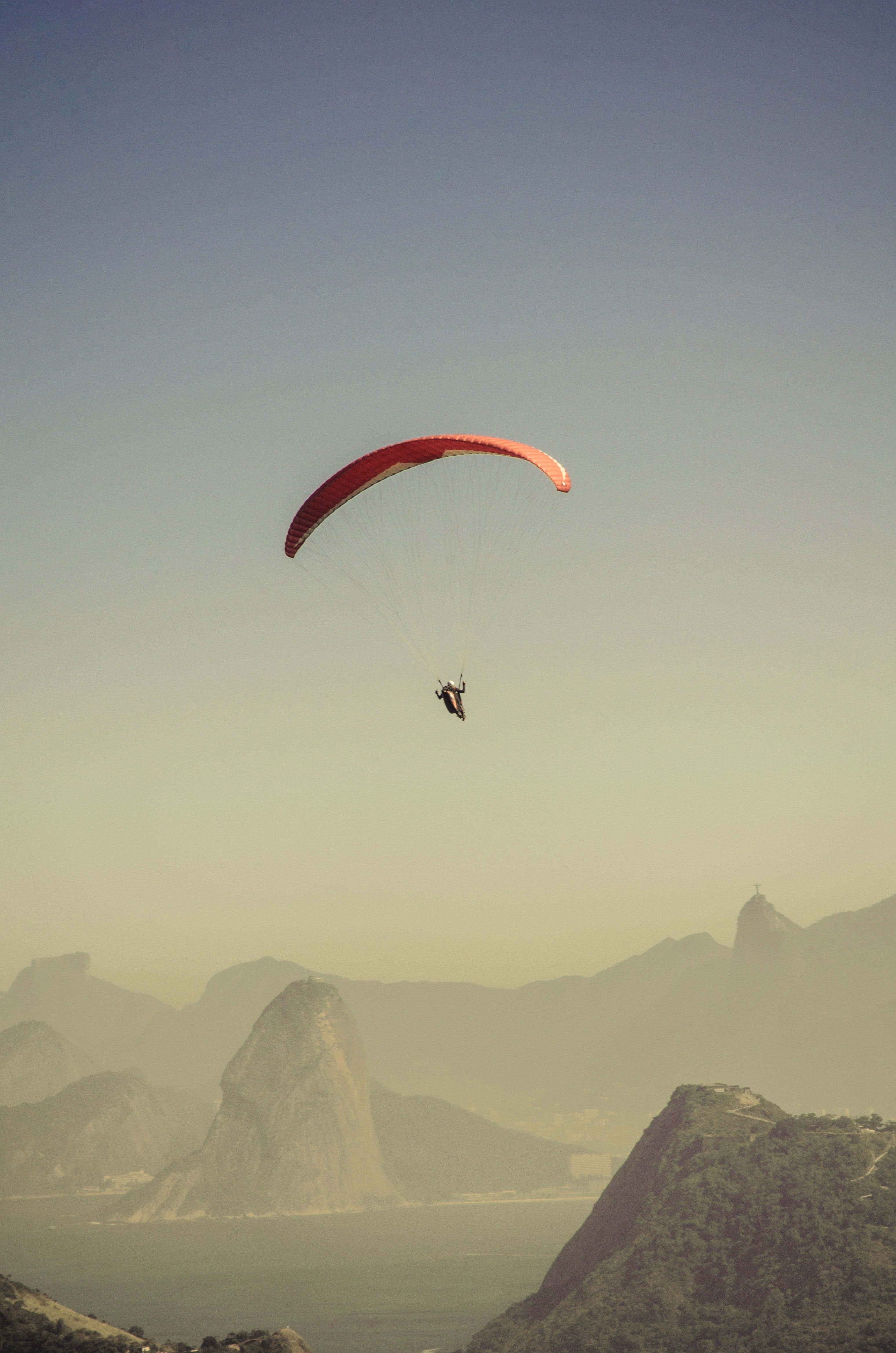 Person in parachute gliding above mountains photo
