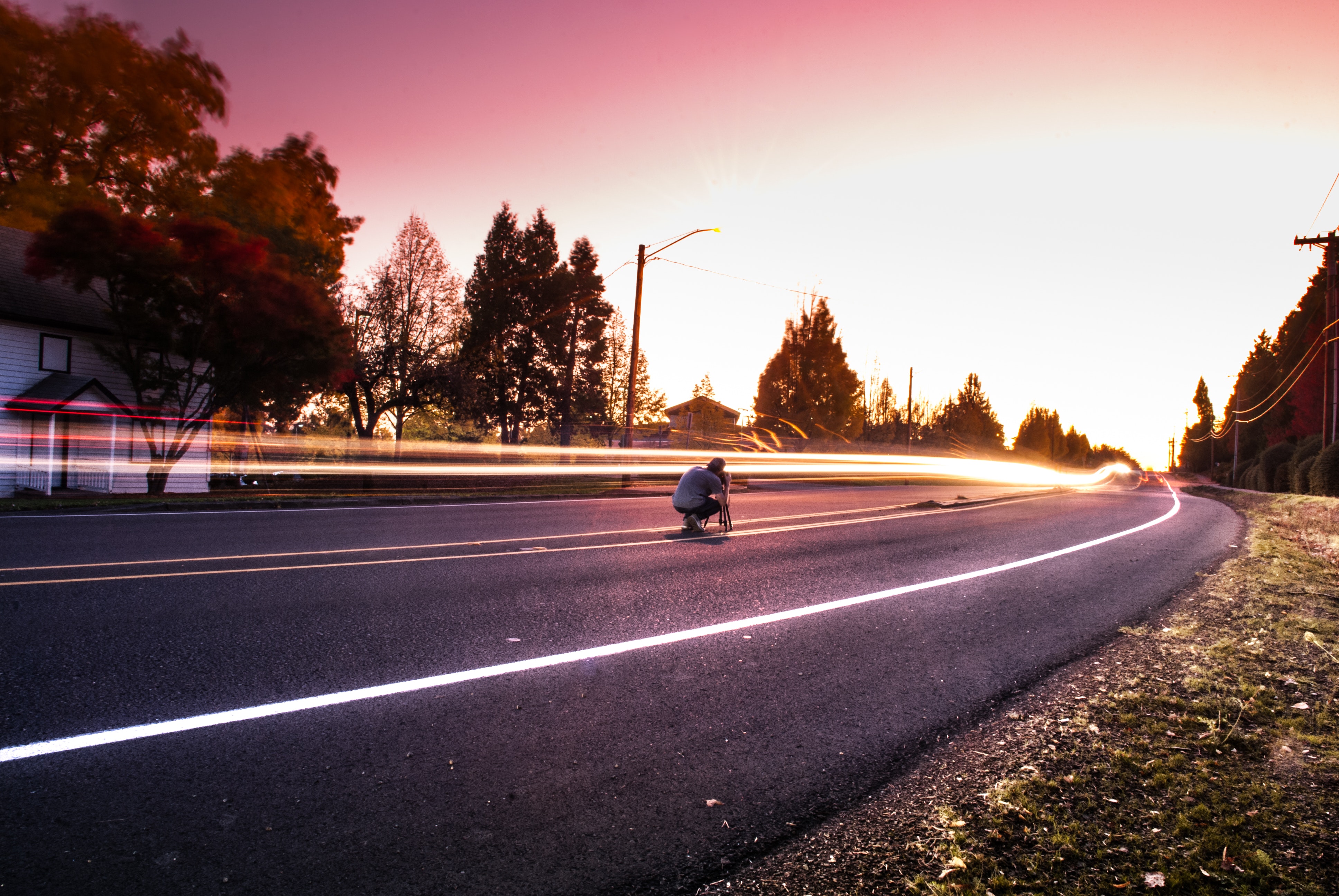 Person sitting on black top road during twilight photo