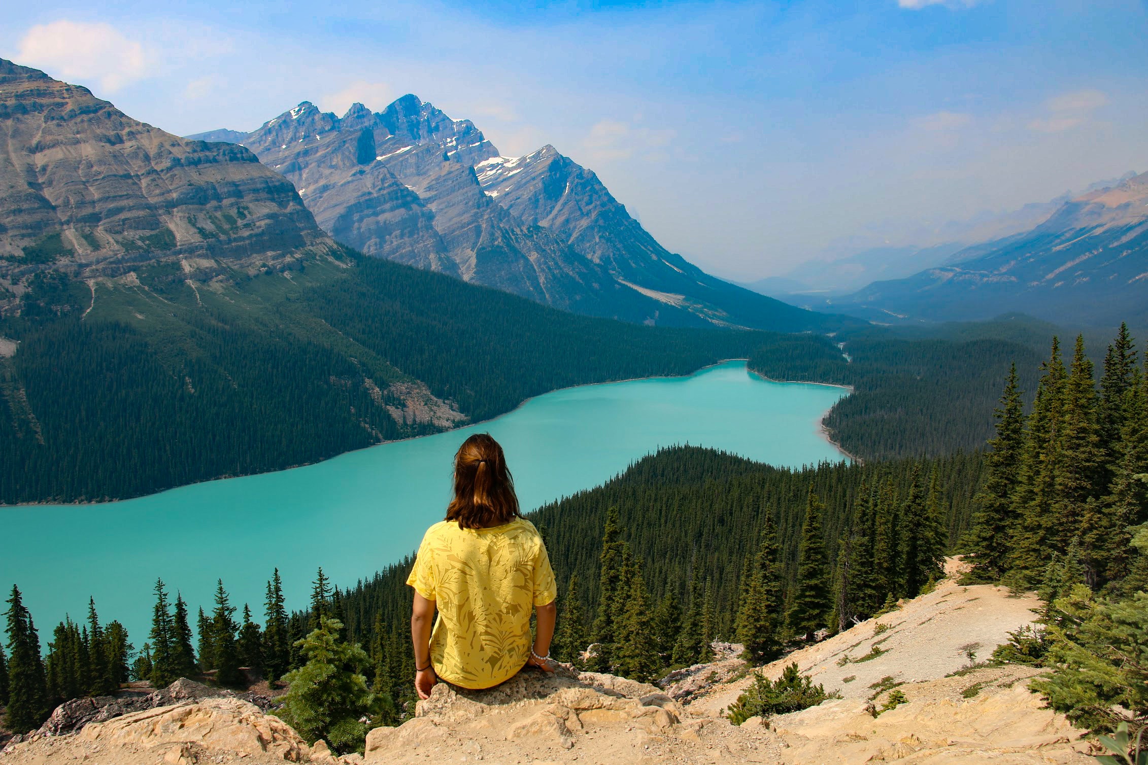 Person sitting on rocky mountain near body of water photo