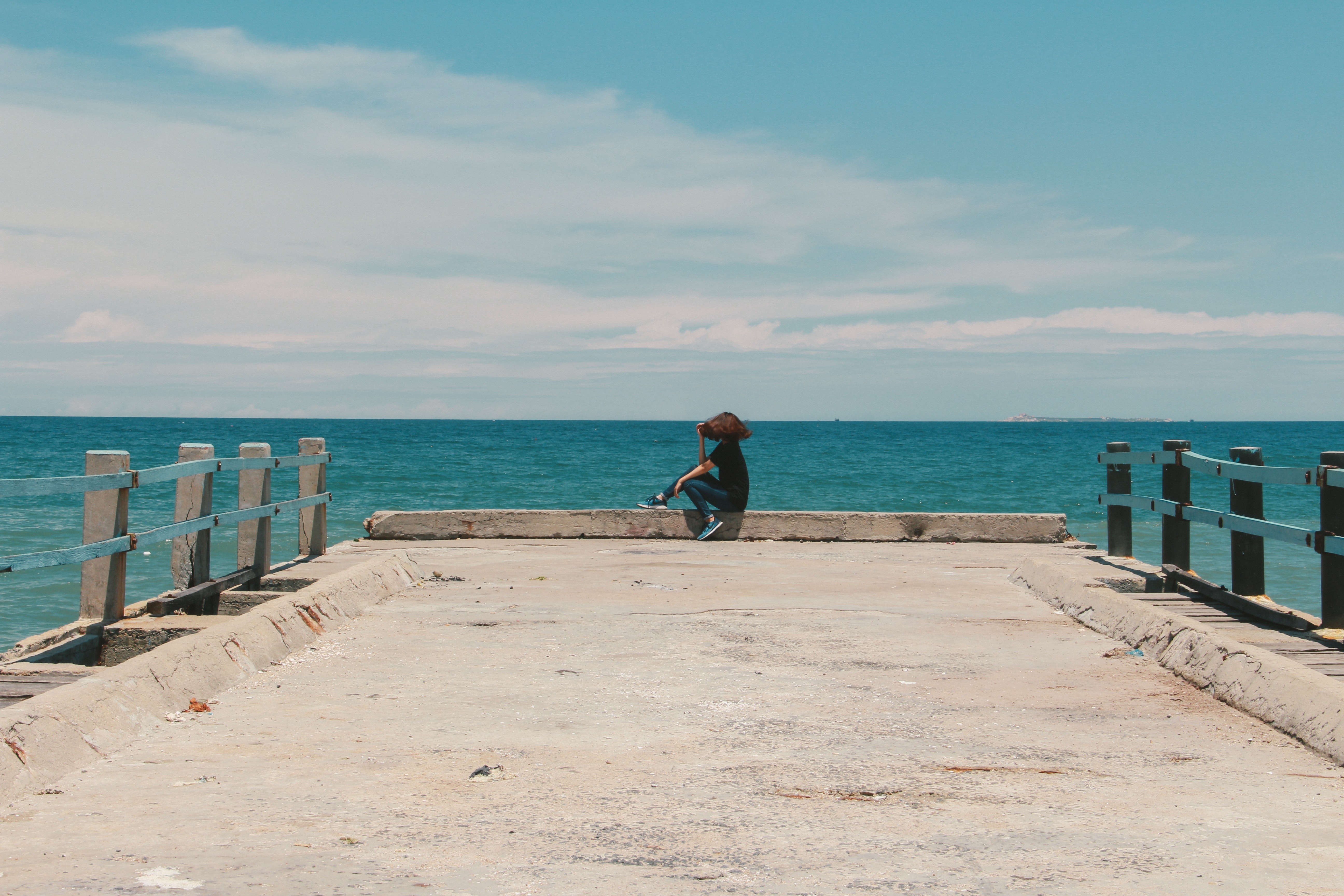 Person sitting on the edge of the beach dock photo