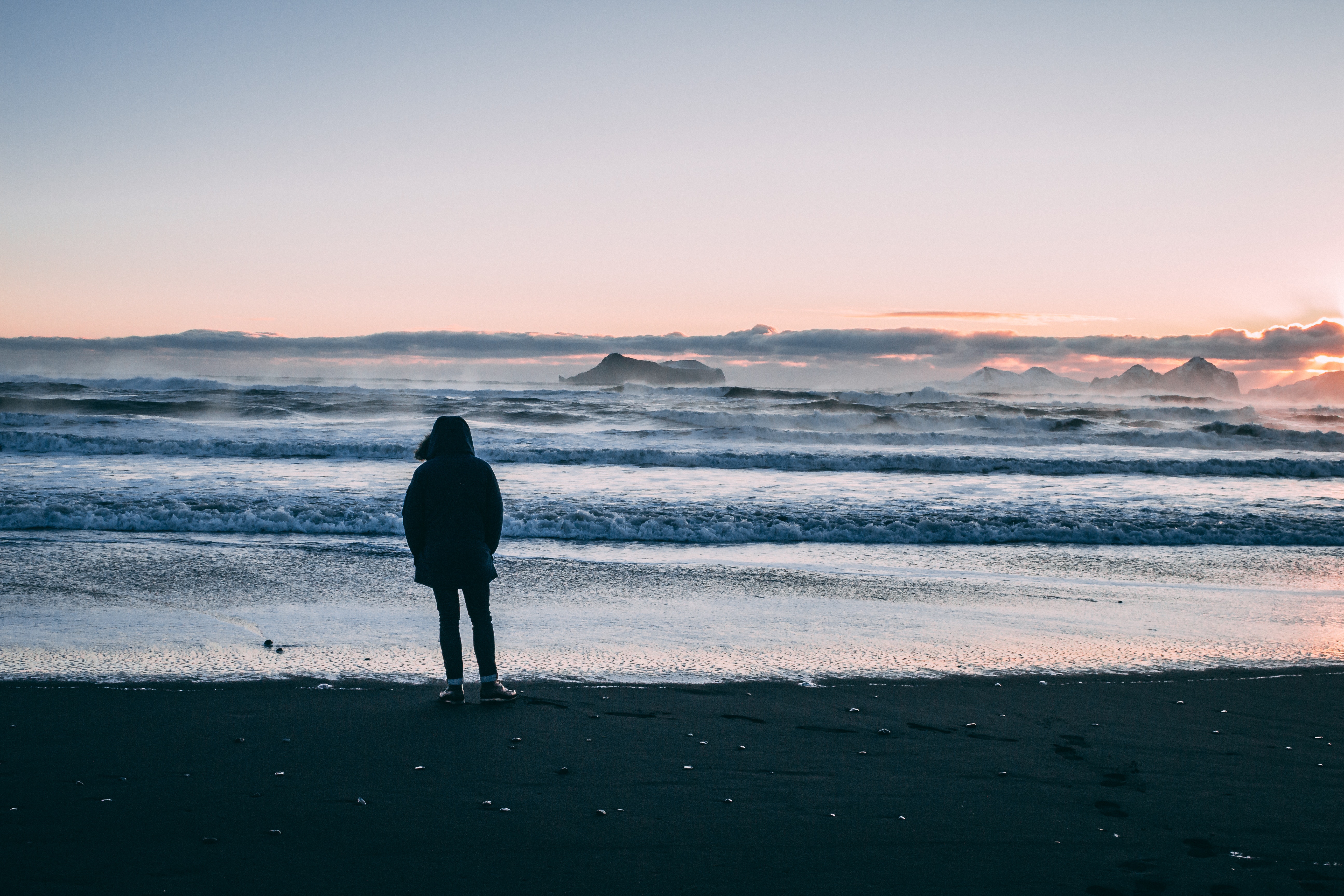 Person standing on beach seashore during sunset photo
