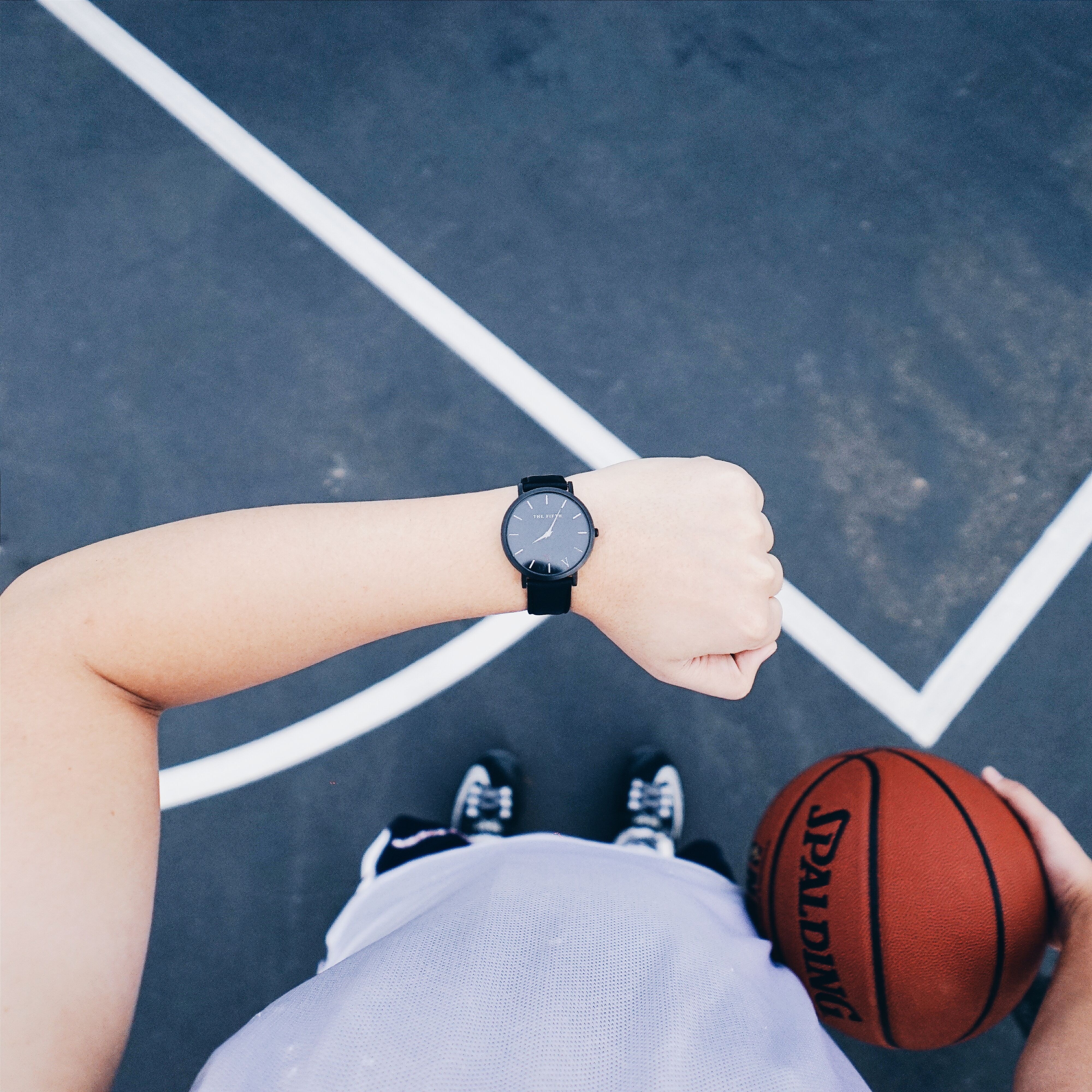 Person wearing black round analog watch on left wrist while holding basketball on right hand photo