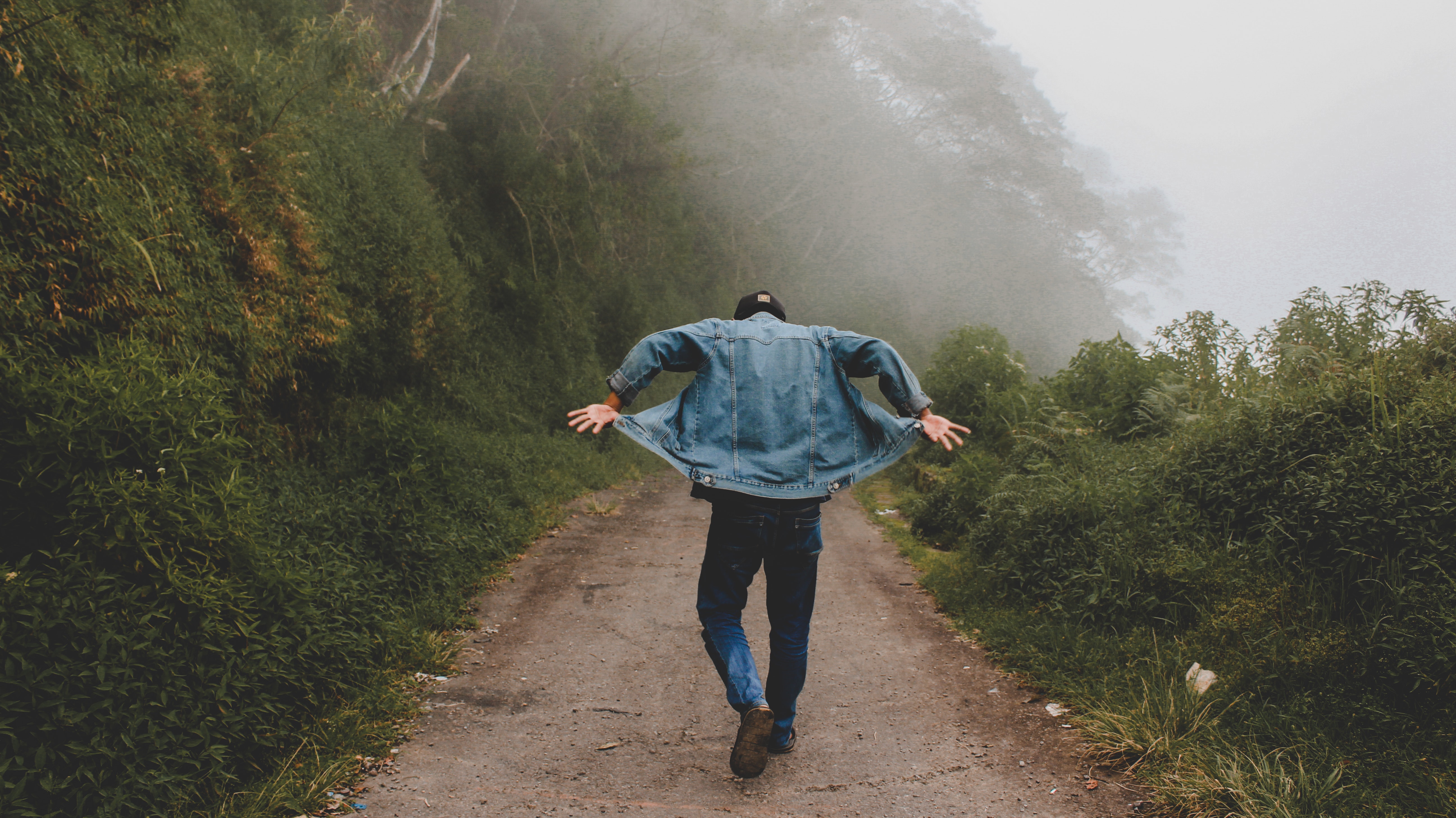 Person wearing blue denim jacket while walking on foggy road photo