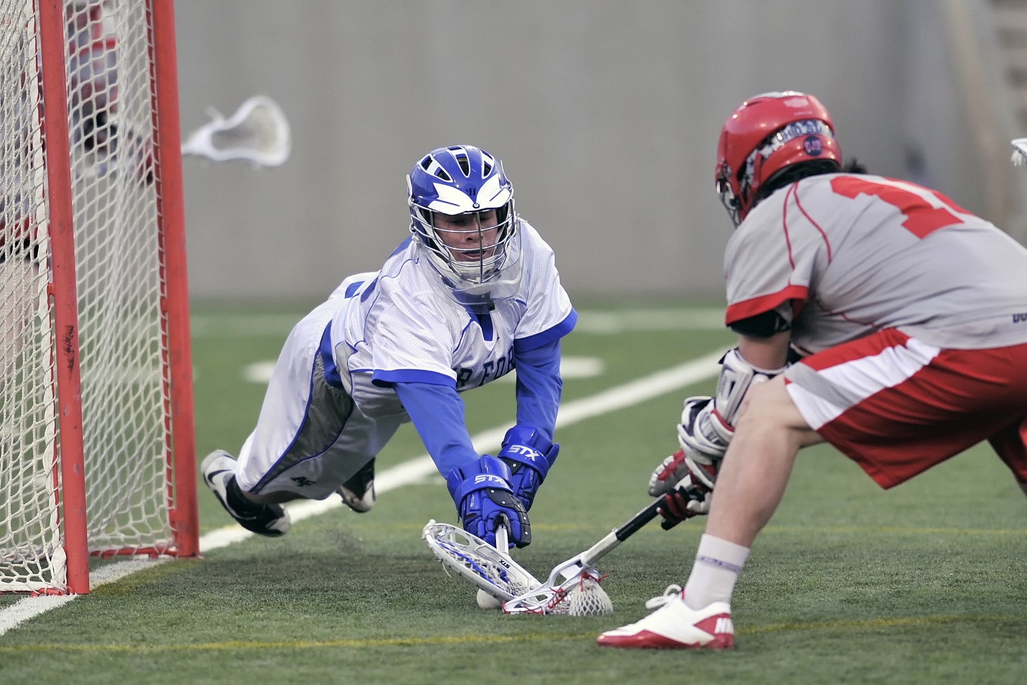 Person wearing blue gloves holding lacrosse stick photo