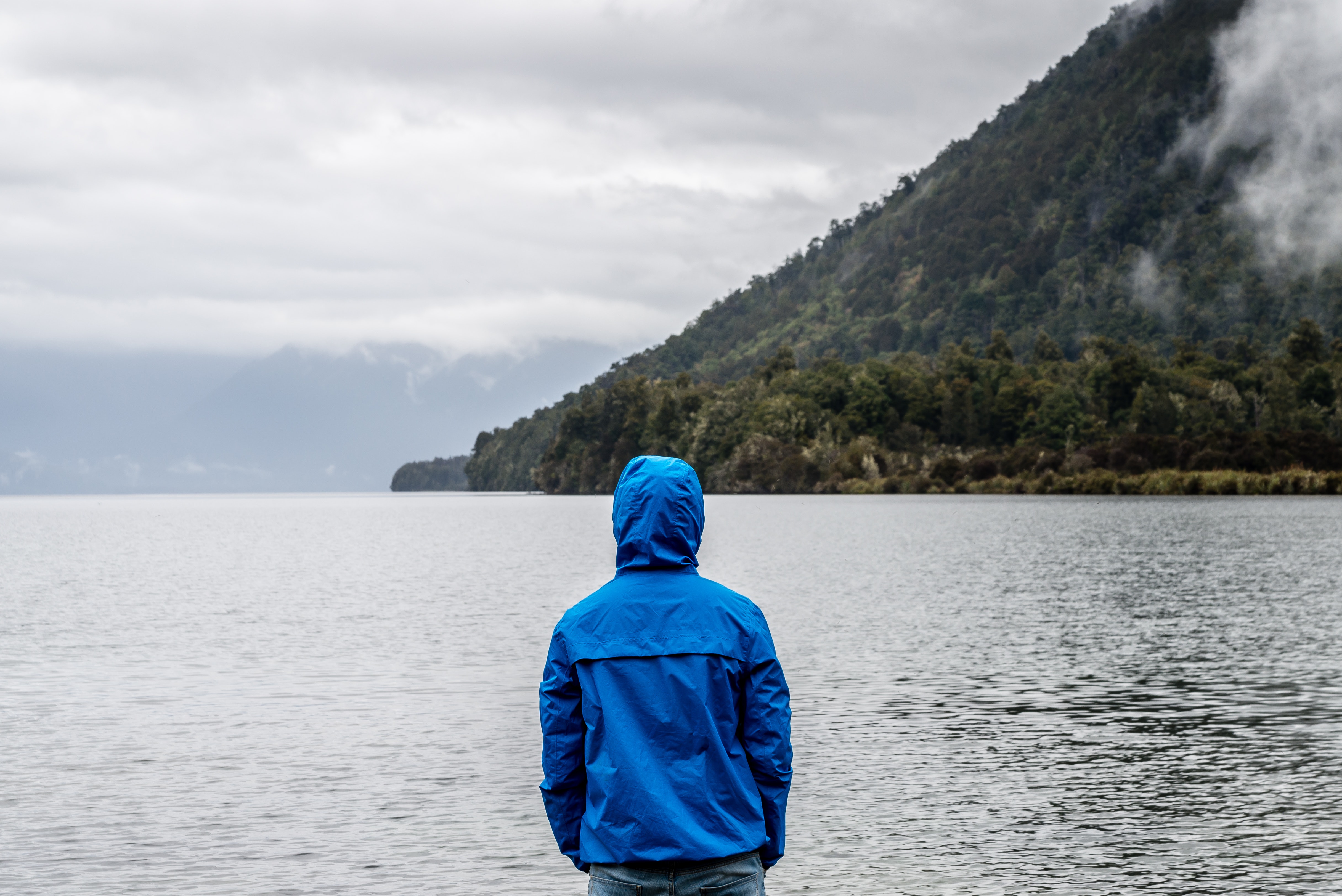Person wearing blue hoodie near body of water photo