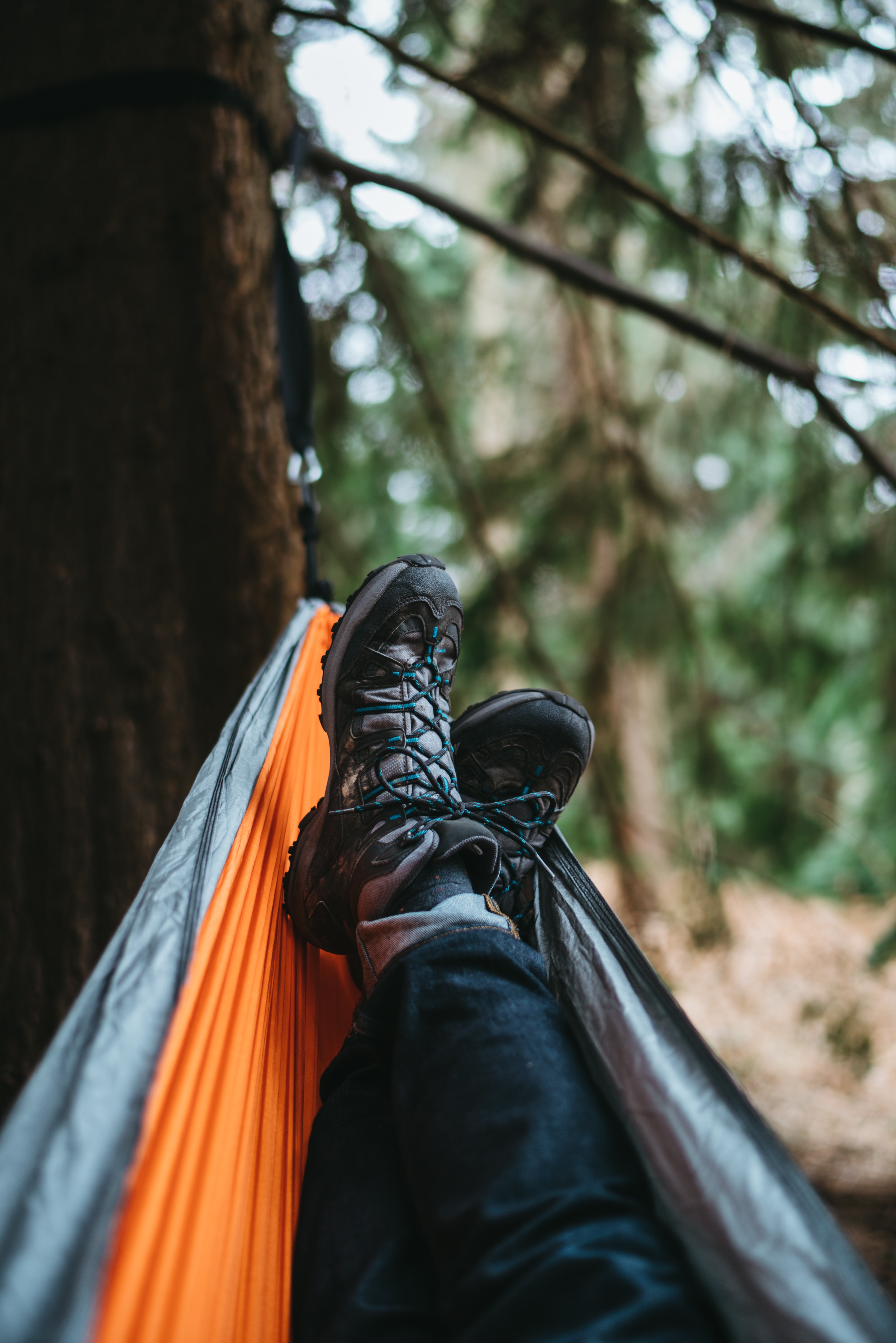 Person wearing pair of black hiking shoes lying on orange and gray hammock photo