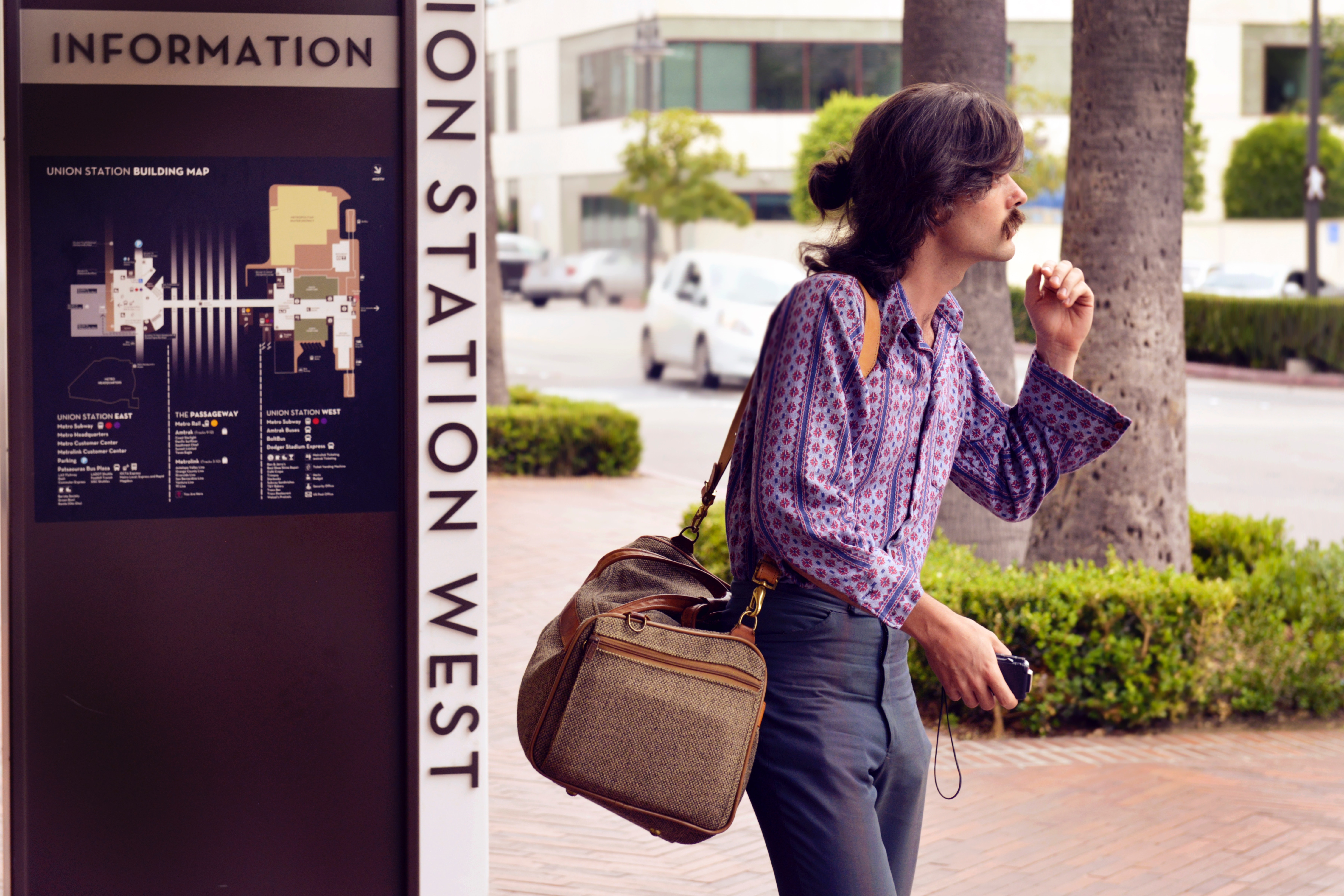 Person wearing purple dress shirt and black pants white carrying brown sling bag photo