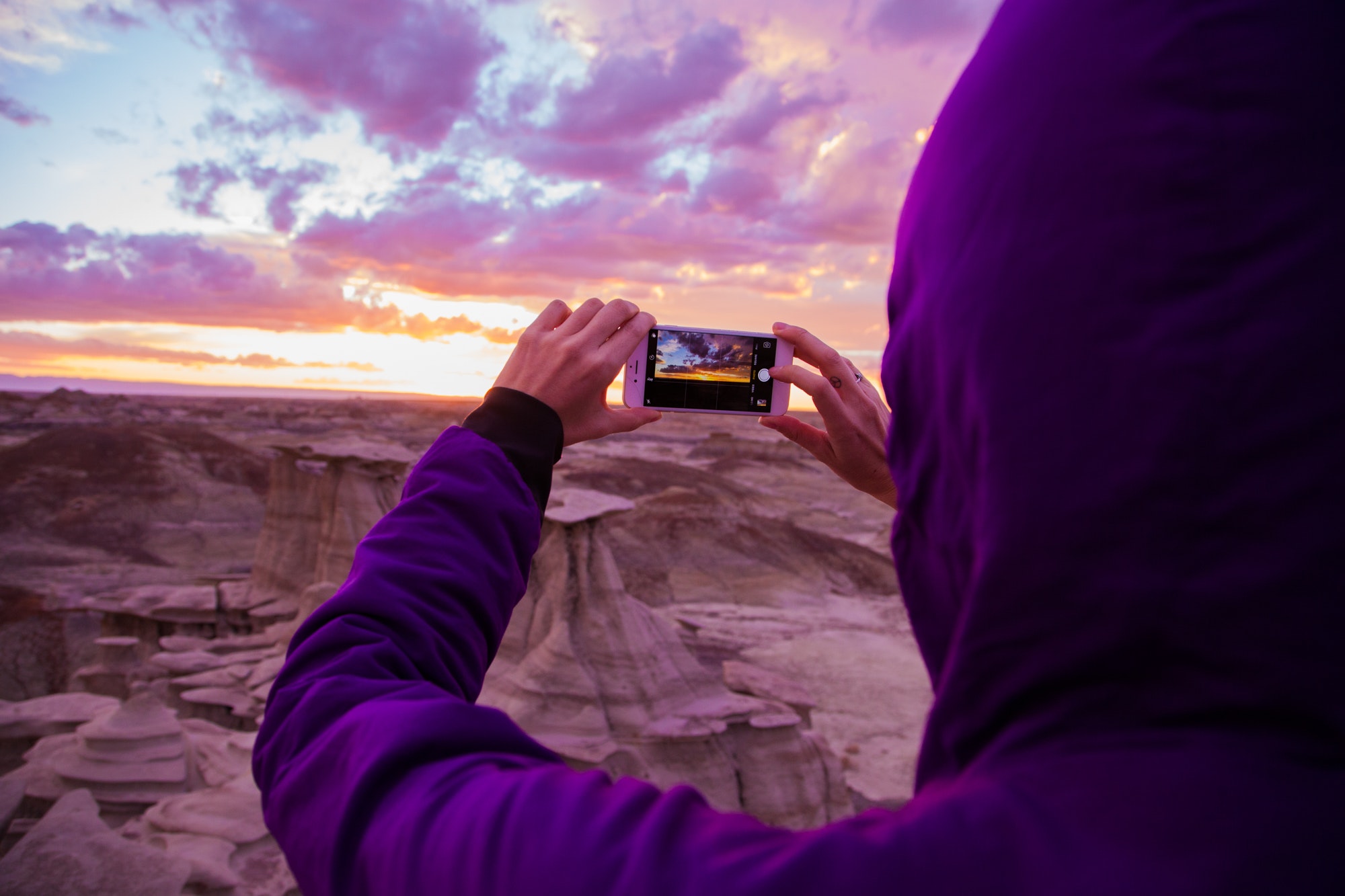 Person wearing purple hoodie jacket holding iphone 6 during golden hour photo