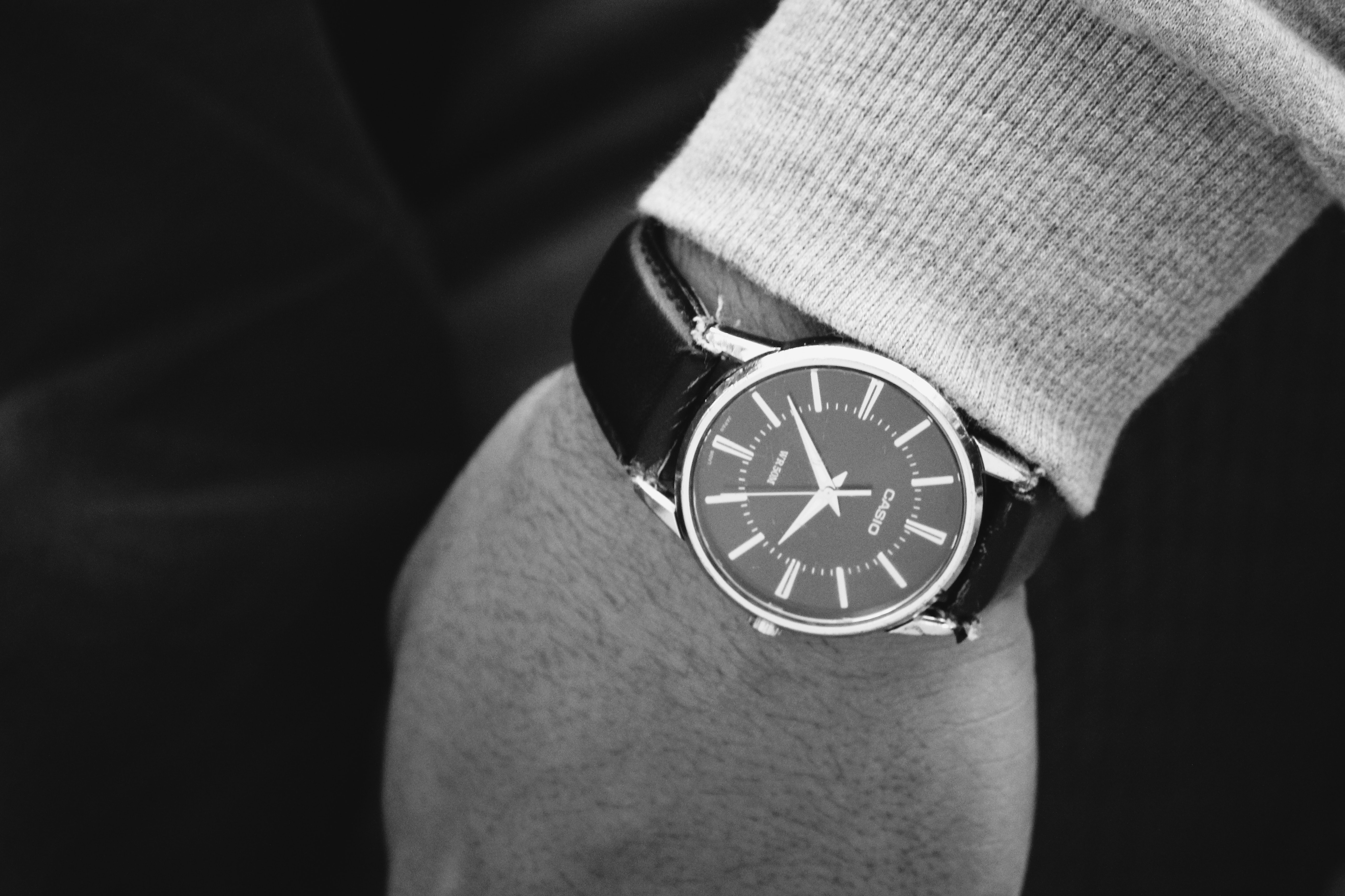 Person wearing round silver analog watch with black leather strap photo