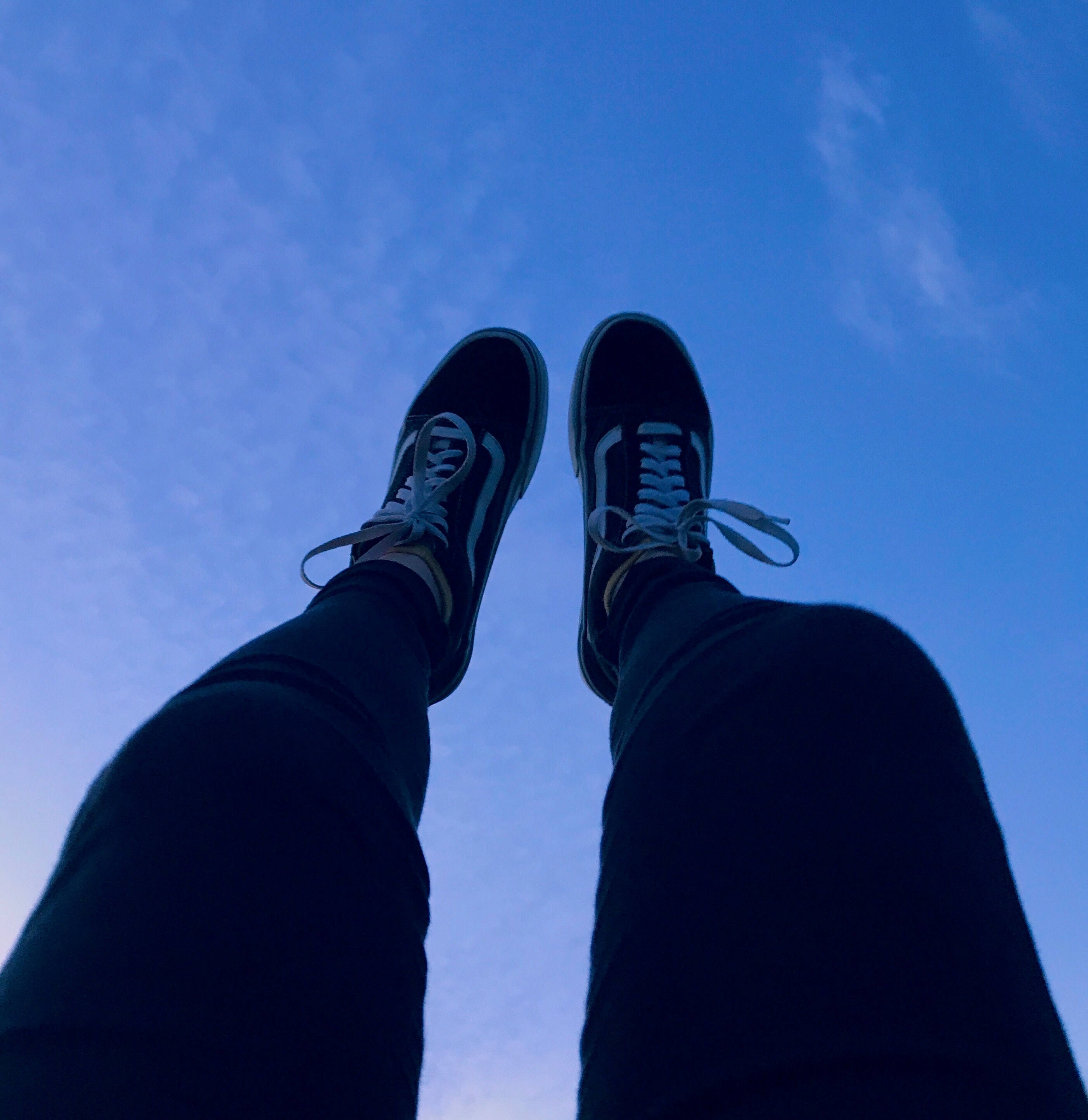 Person wearing vans old skool sneakers raising his feet pointing to they sky photo
