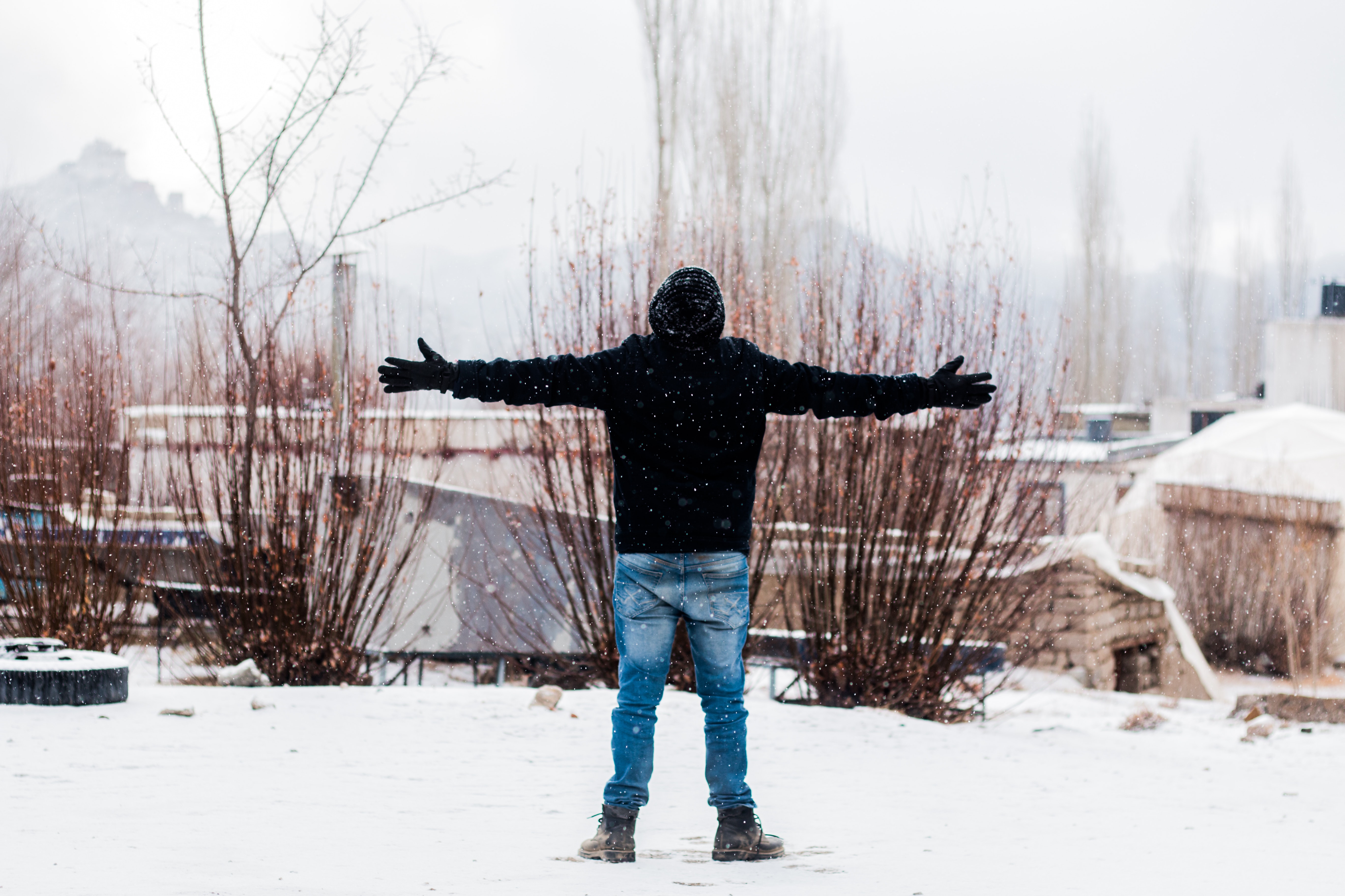 Person wears black jacket and blue denim jeans standing on snow covered field photo