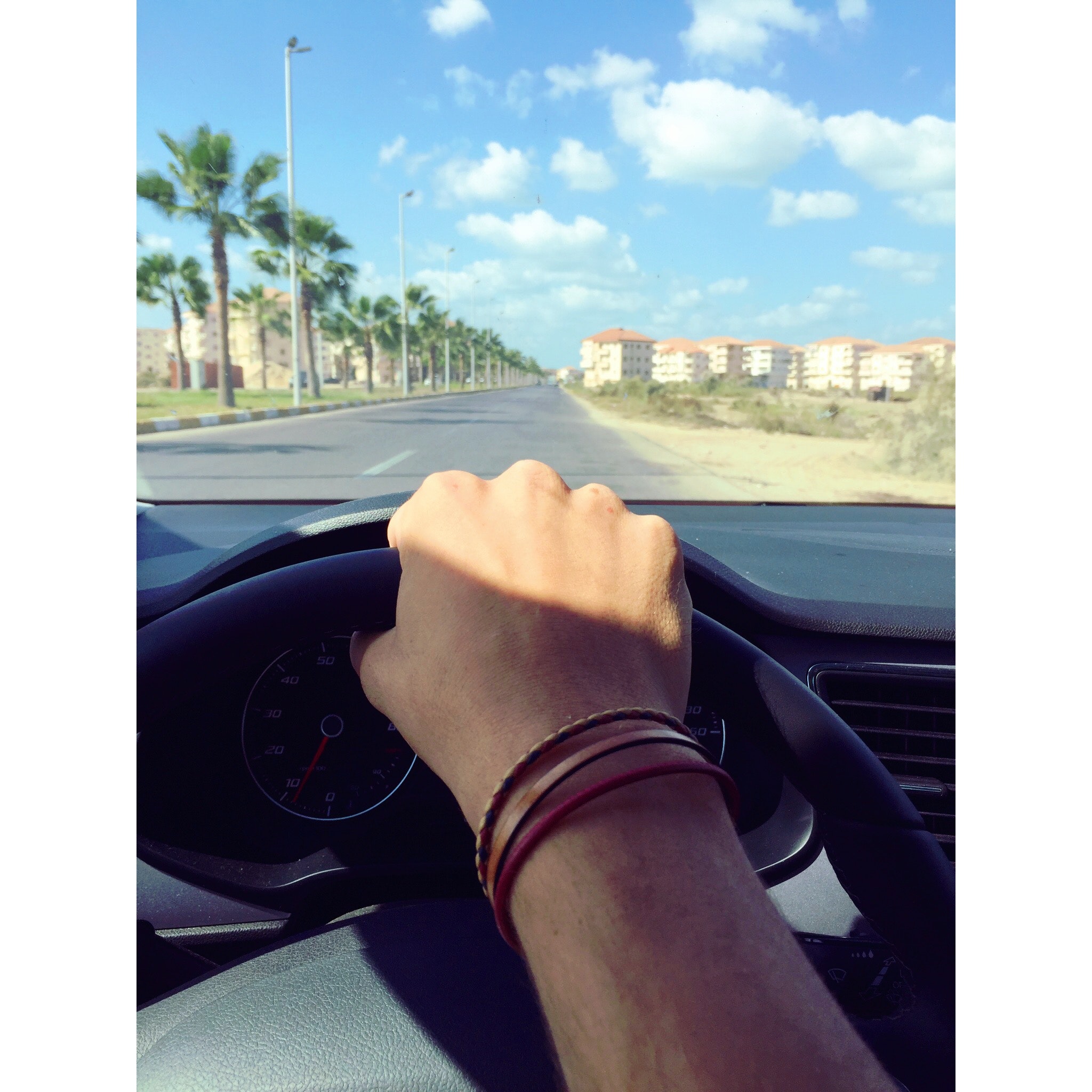 Person withe bracelets holding black steering wheel photo