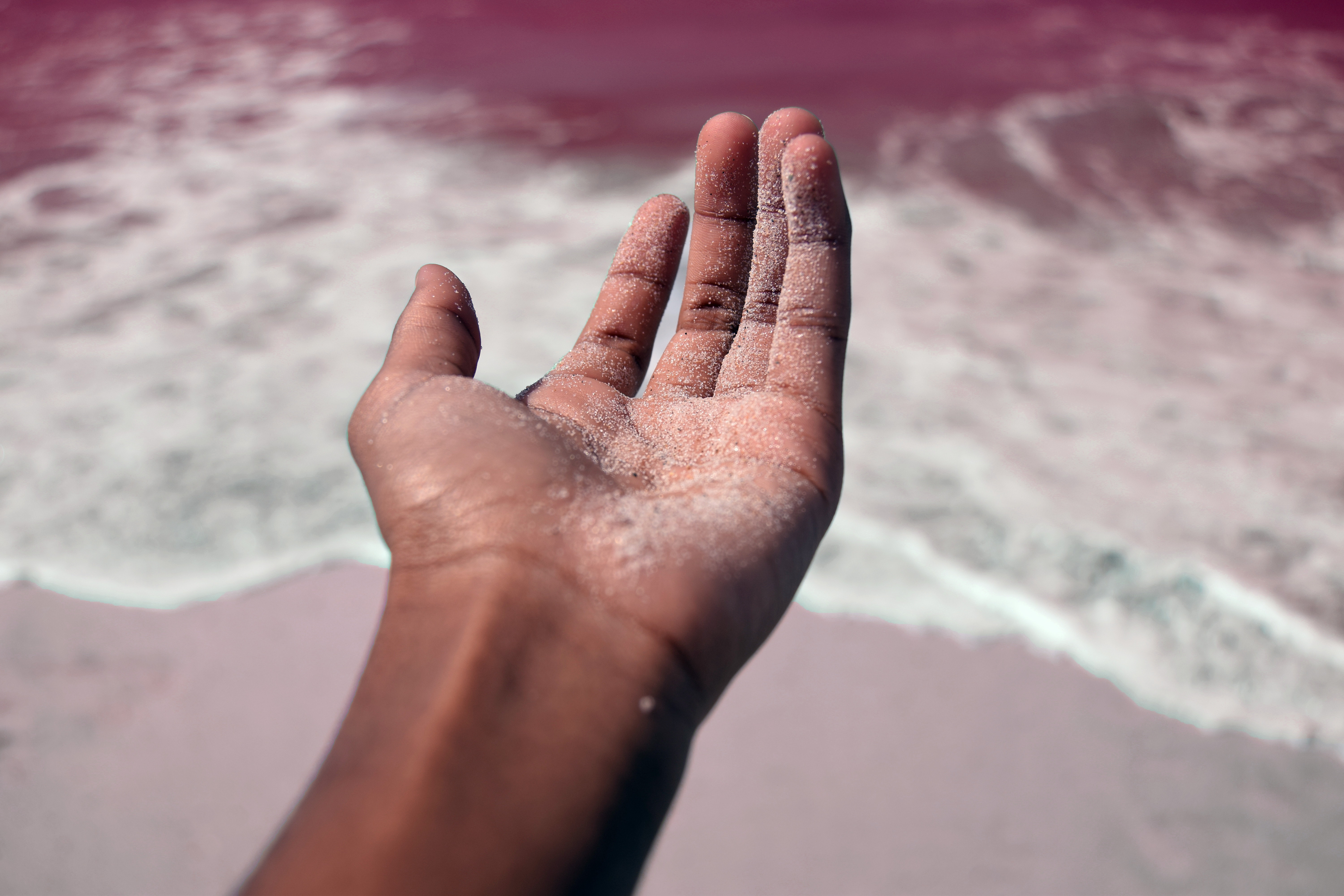 Person's left hand covered with sand photo