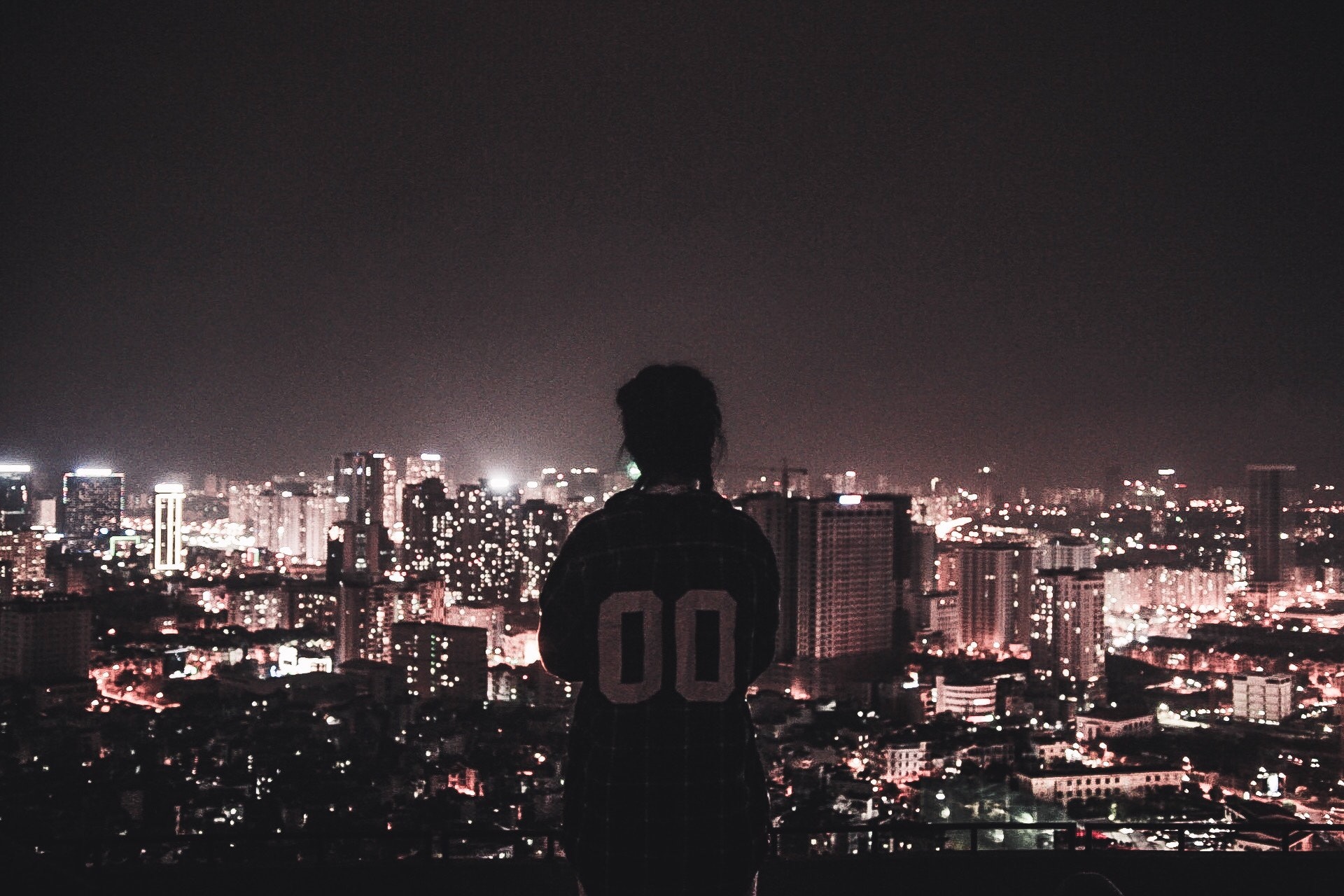 Photo of a person watching over city lights during night time