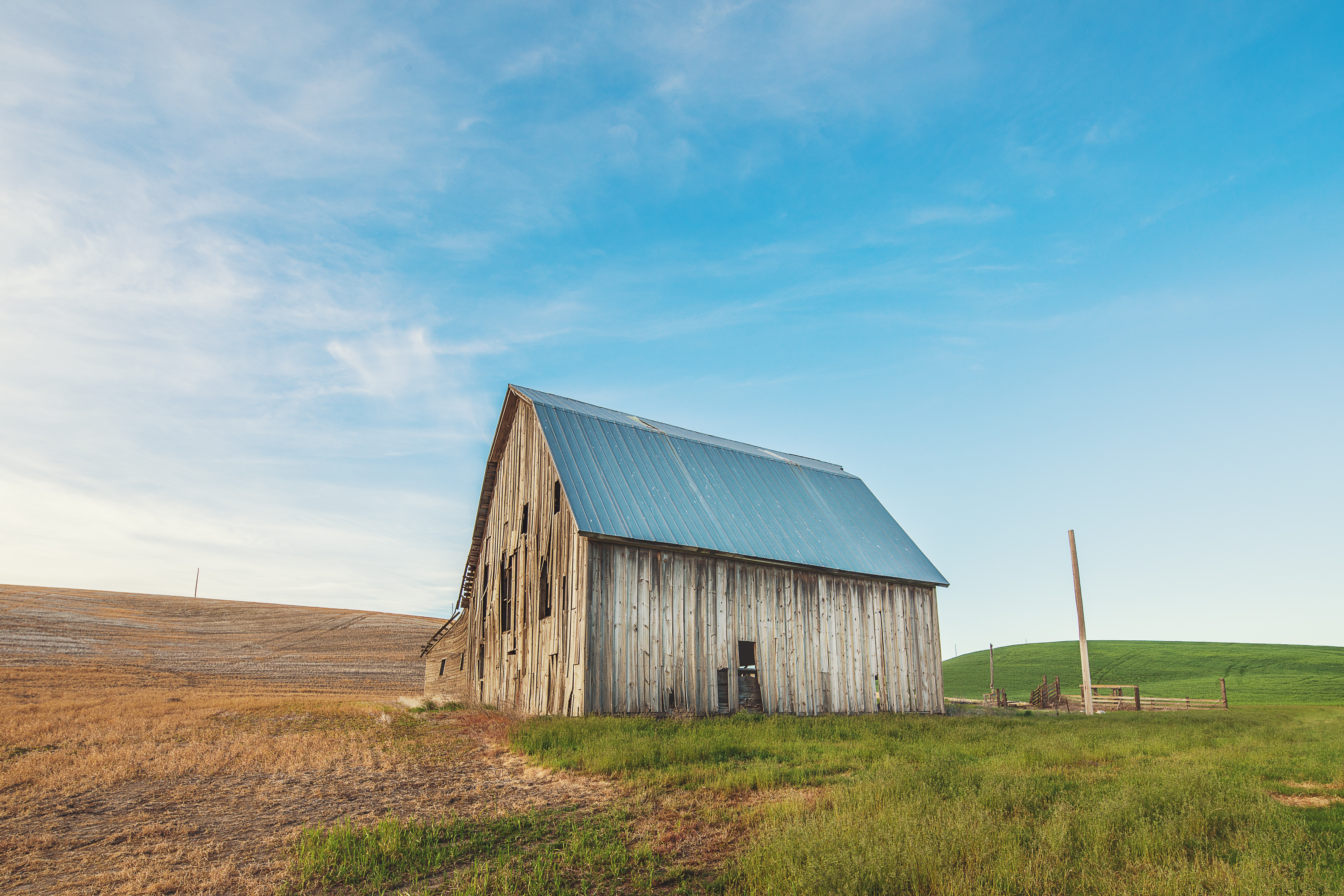 Photo of beige and gray wooden barn house on green grass