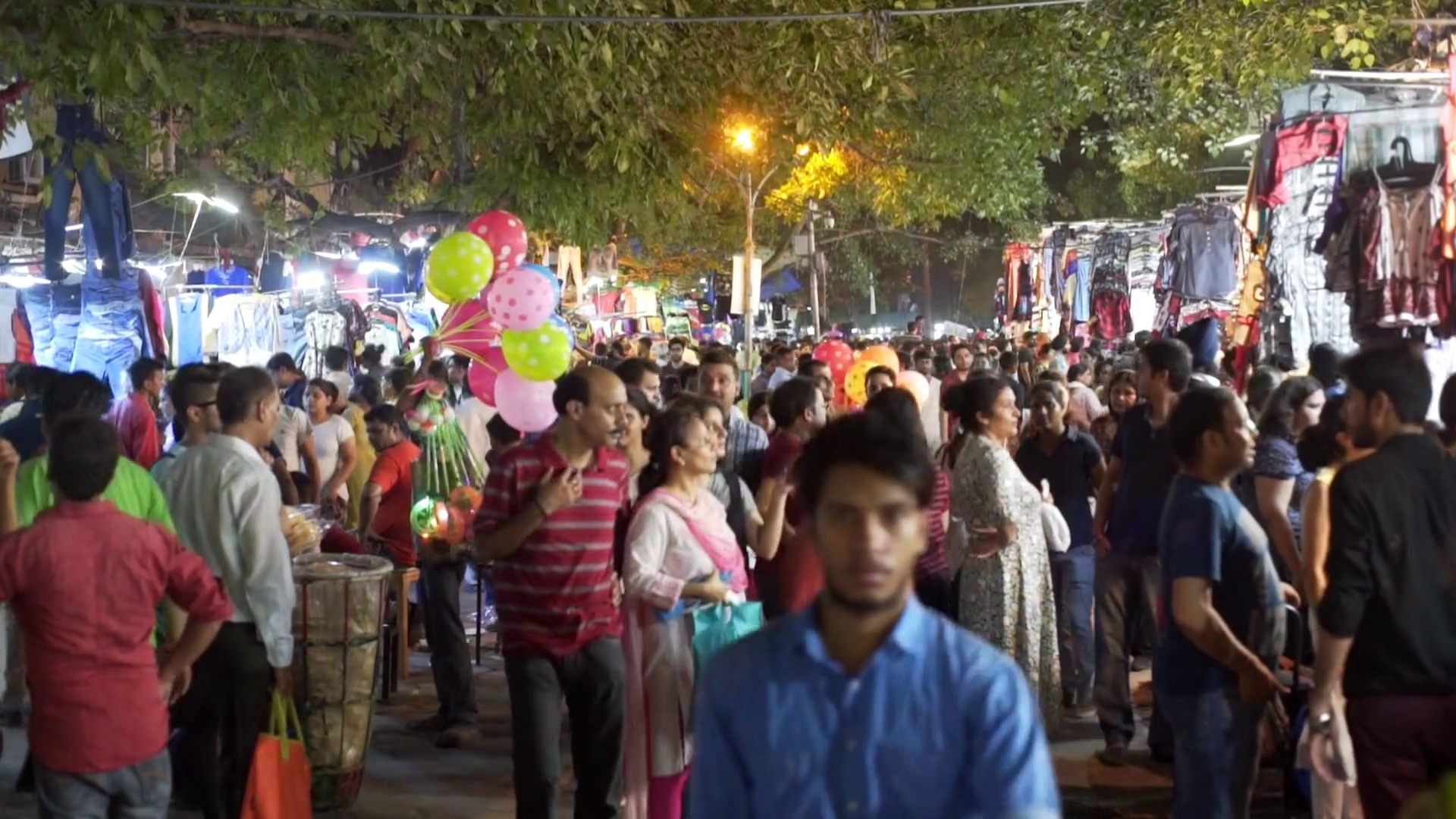 Crowd of people walk, shop for clothes, market, nighttime, New Delhi ...