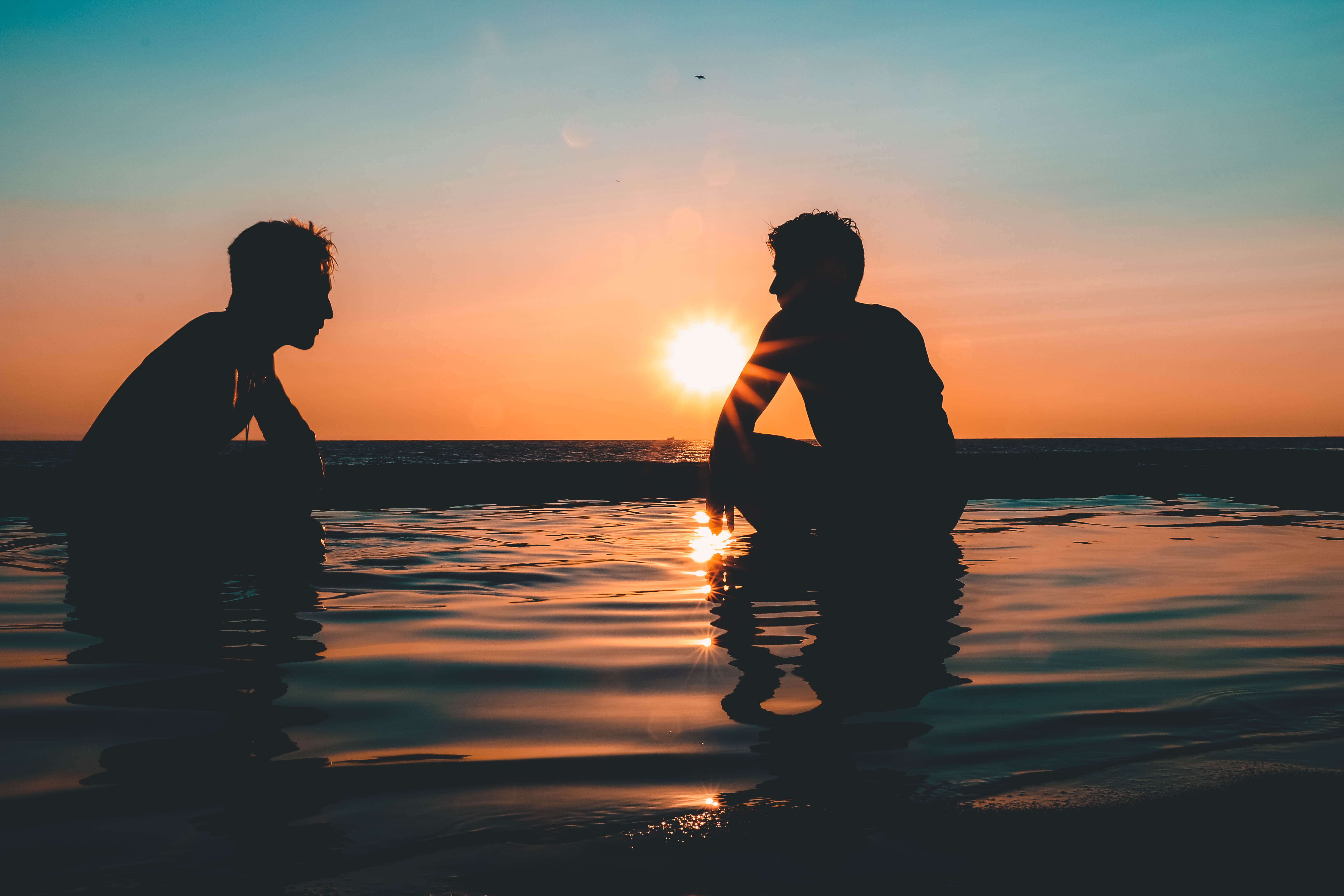 Photo of two men on seashore during sunset