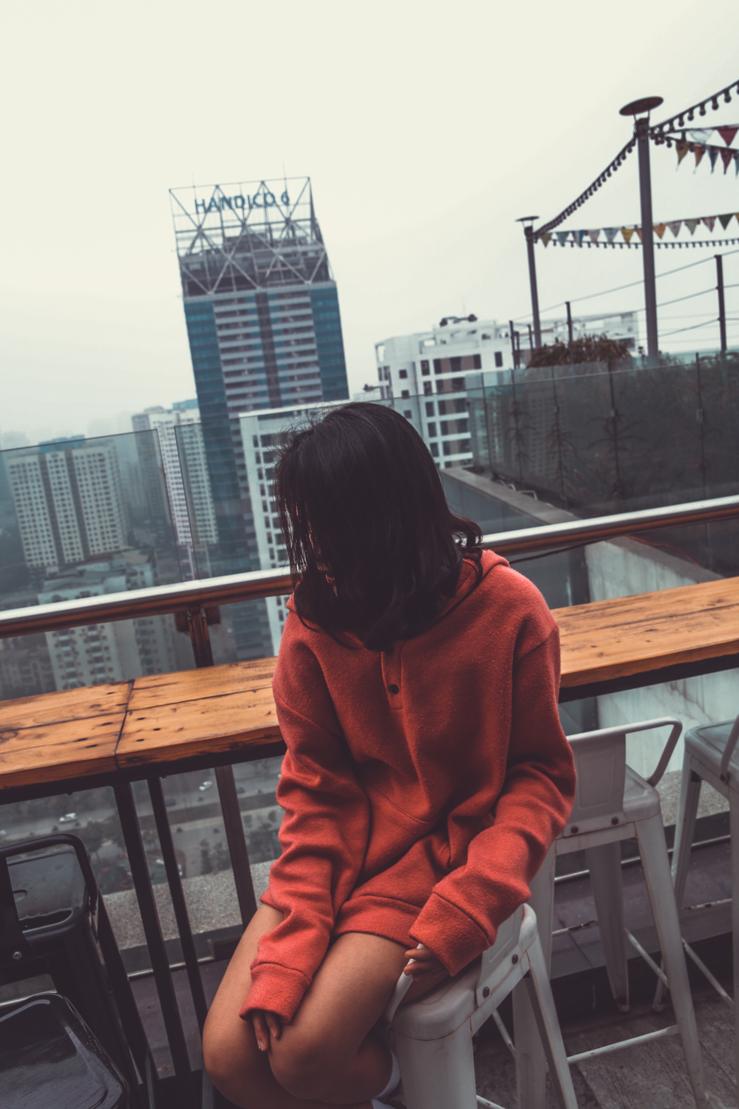 Photograph of woman wearing red pullover hoodie jacket sitting on white barstool