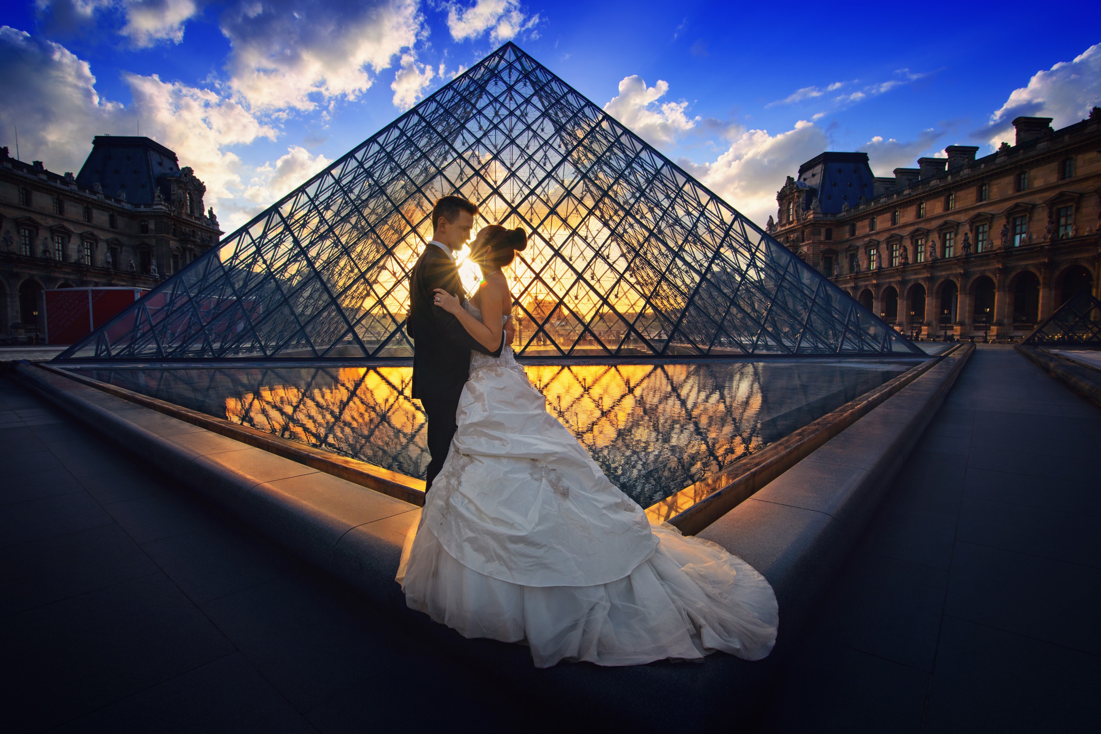 Photography of man and woman at the lourve museum during sunset