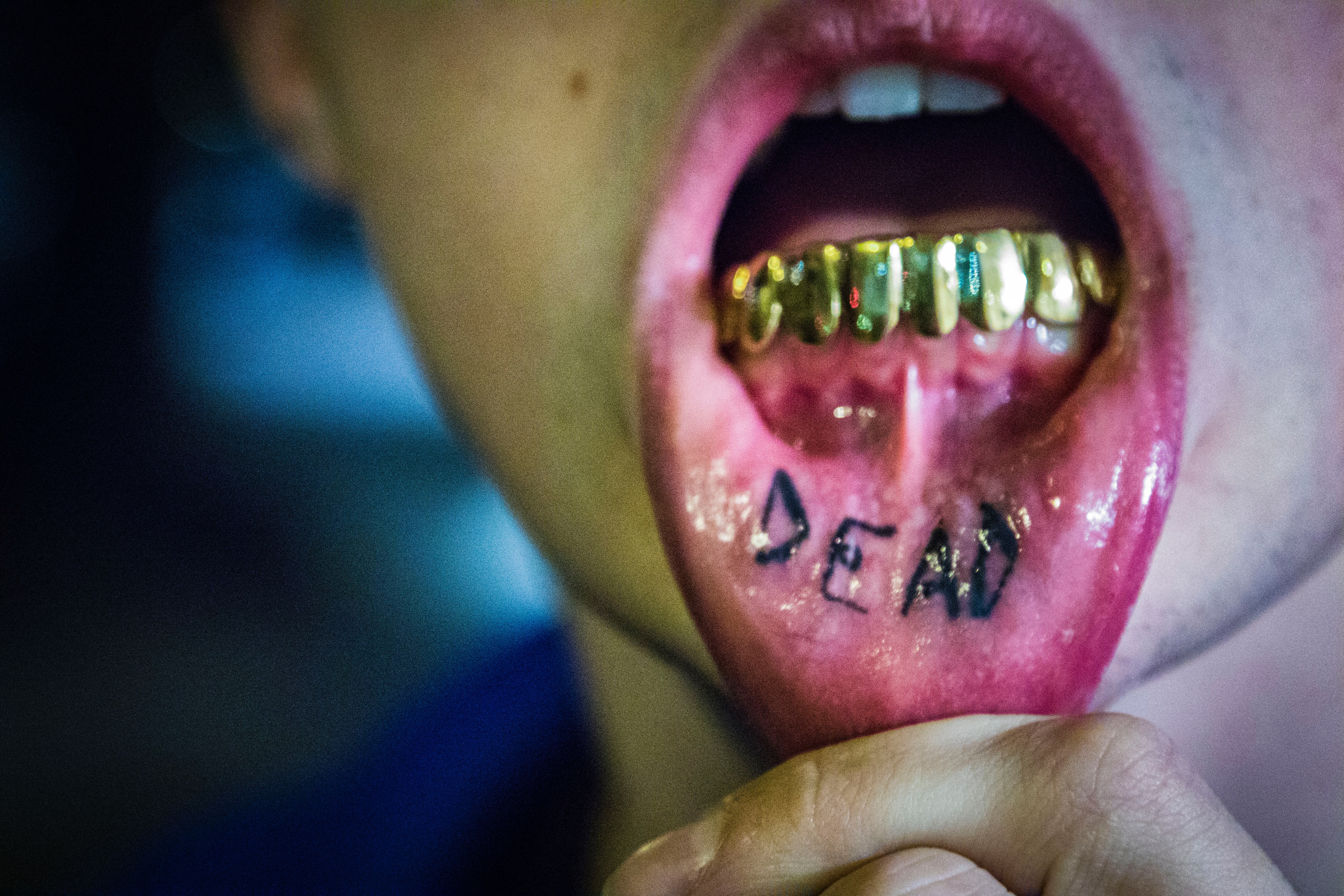 Photography of man showing tattoo and gold teeth
