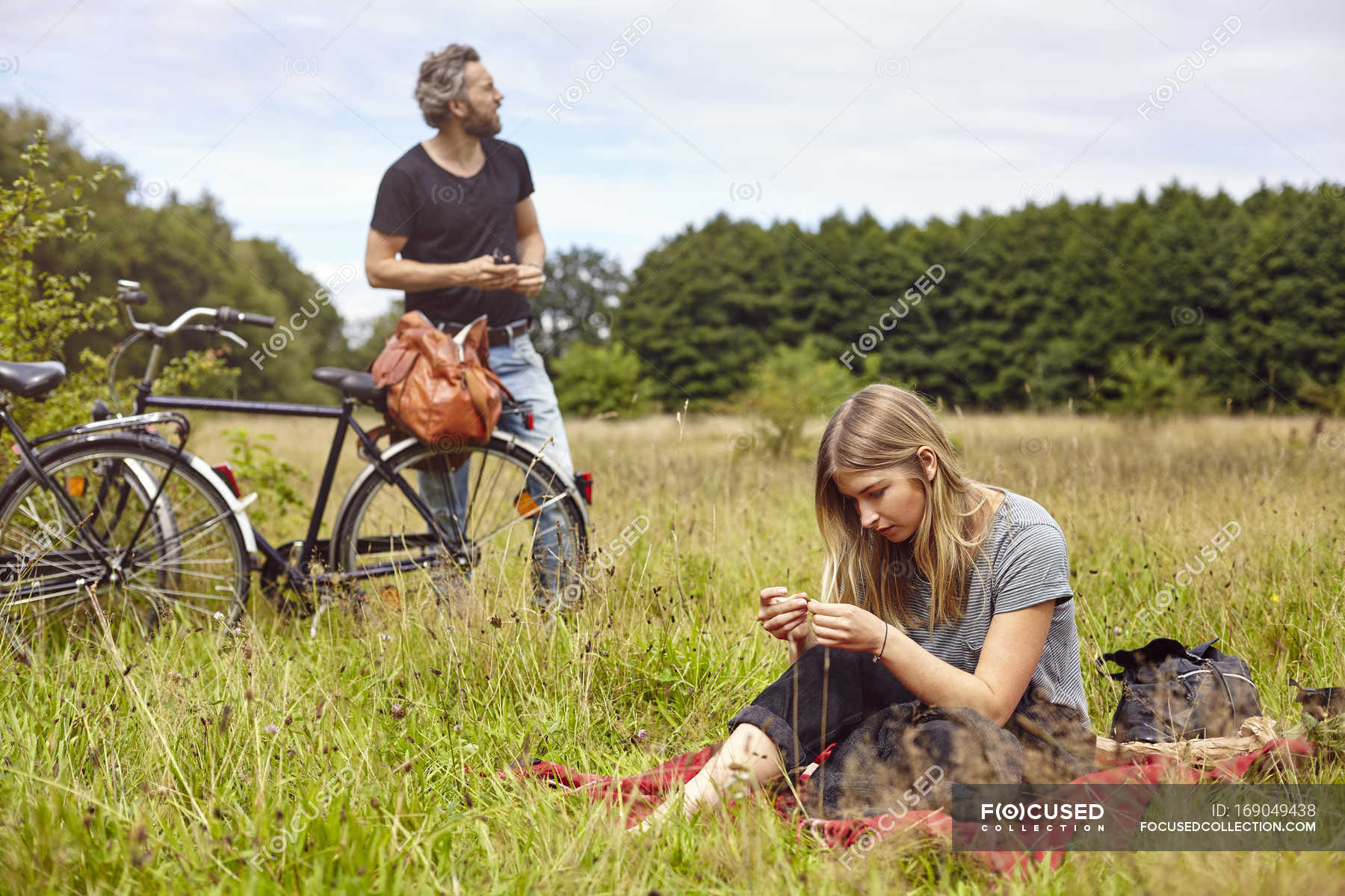 Couple with bicycles picnicing in rural field — Stock Photo | #169049438