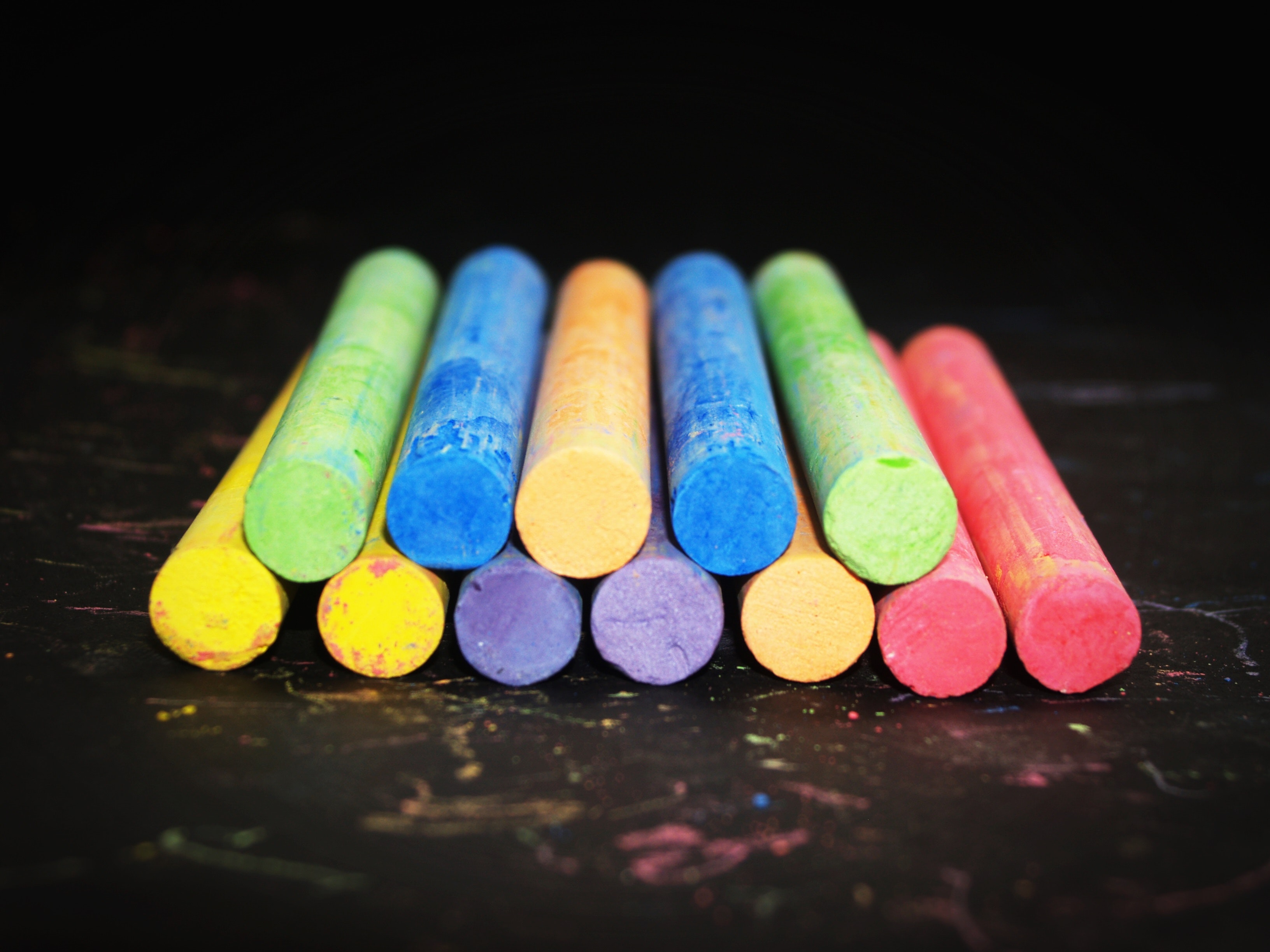 Pile of colored chalk on black wooden tabletop photo