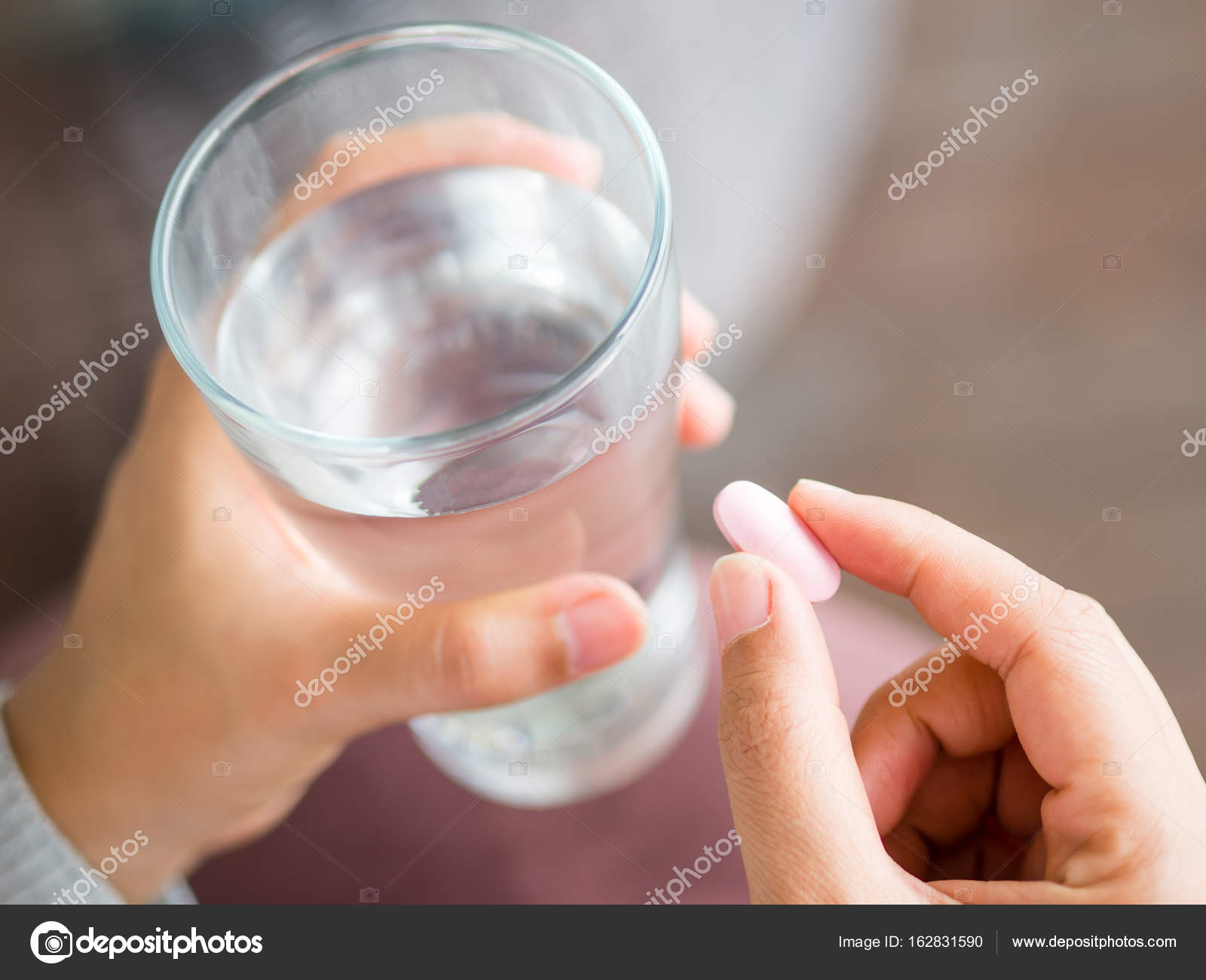 Closeup woman hand with pills medicine tablets and glass of water in ...