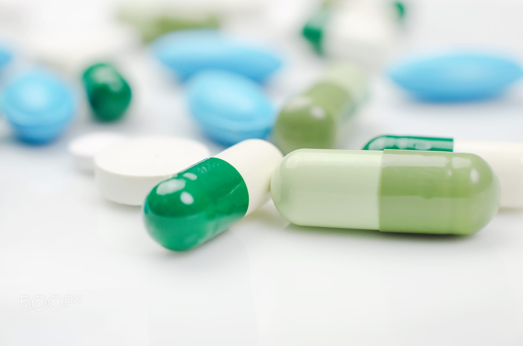Close-up. Pharmacy theme. Blue and green pills on the white surface ...