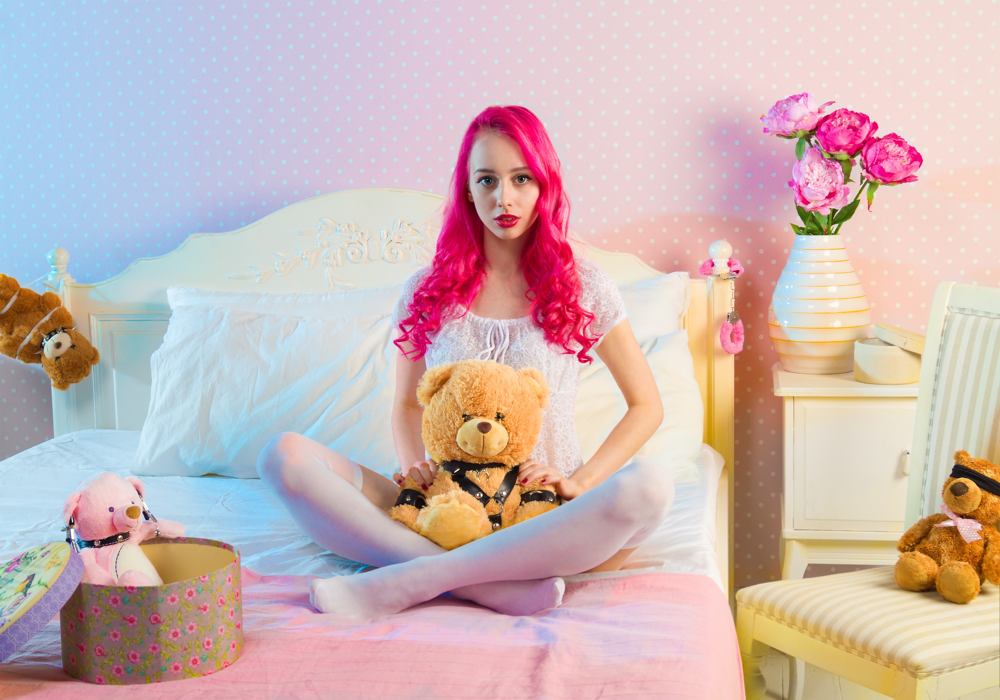 Pink long haired woman sitting on double bed with bear plsuh toy at daylight photo