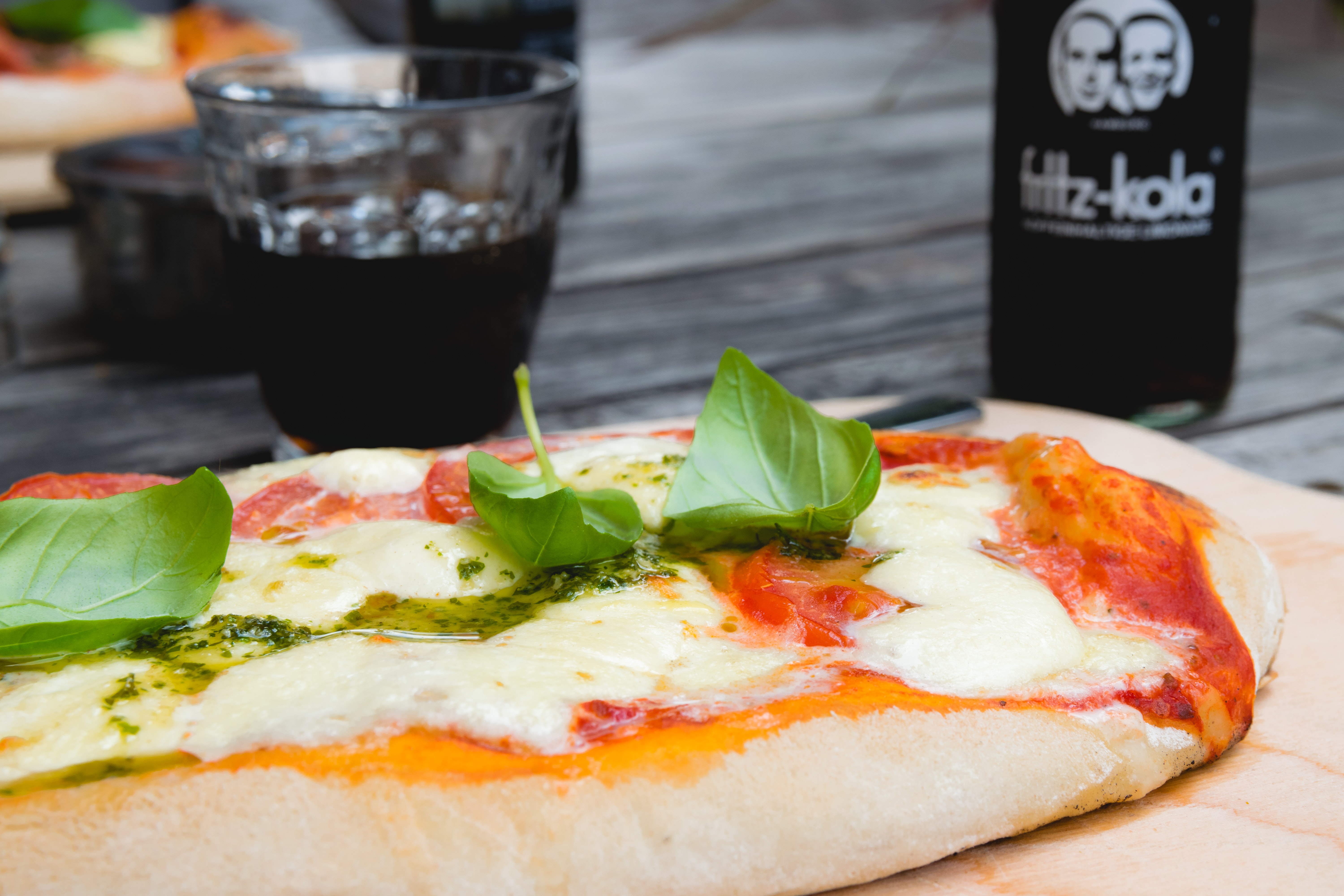Pizza Top With Green Leafy Vegetable Near Glass of Black Liquid, Basil, Mozzarella, Wooden table, Tomatoes, HQ Photo