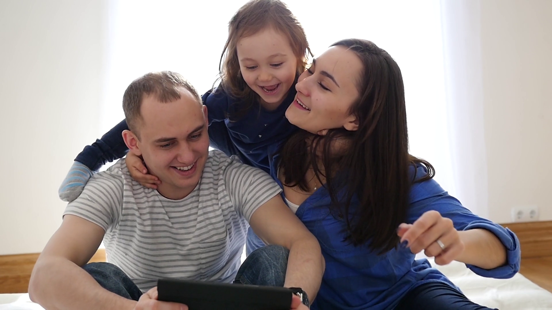 Happy Family Idyll Couple With Tablet Hug Their Playful Little Child ...