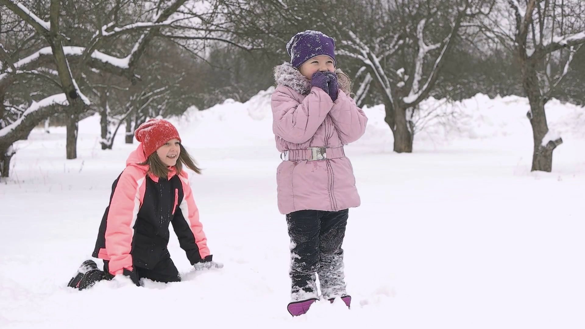 Slow motion of joyful kids playing in snow. Two happy girls having ...