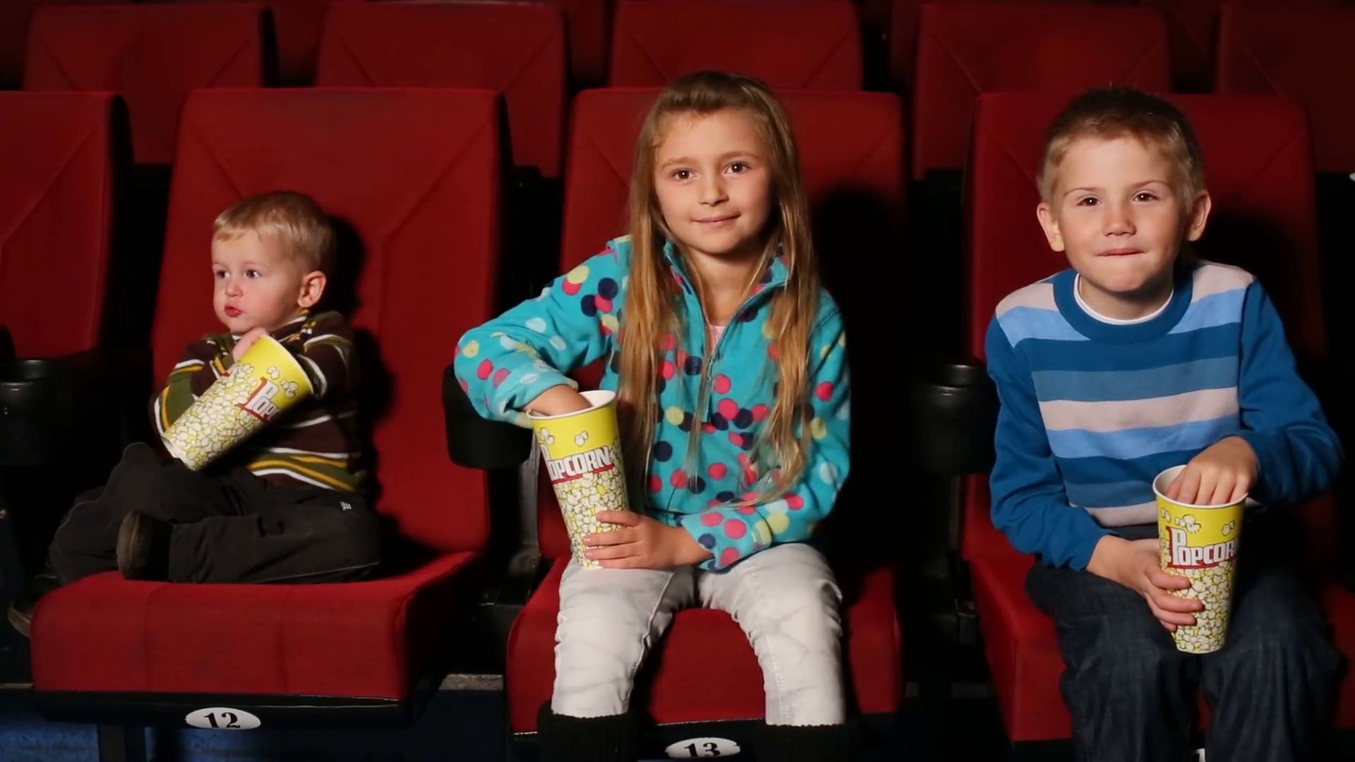 children with popcorn in hand watching a movie at the cinema Stock ...
