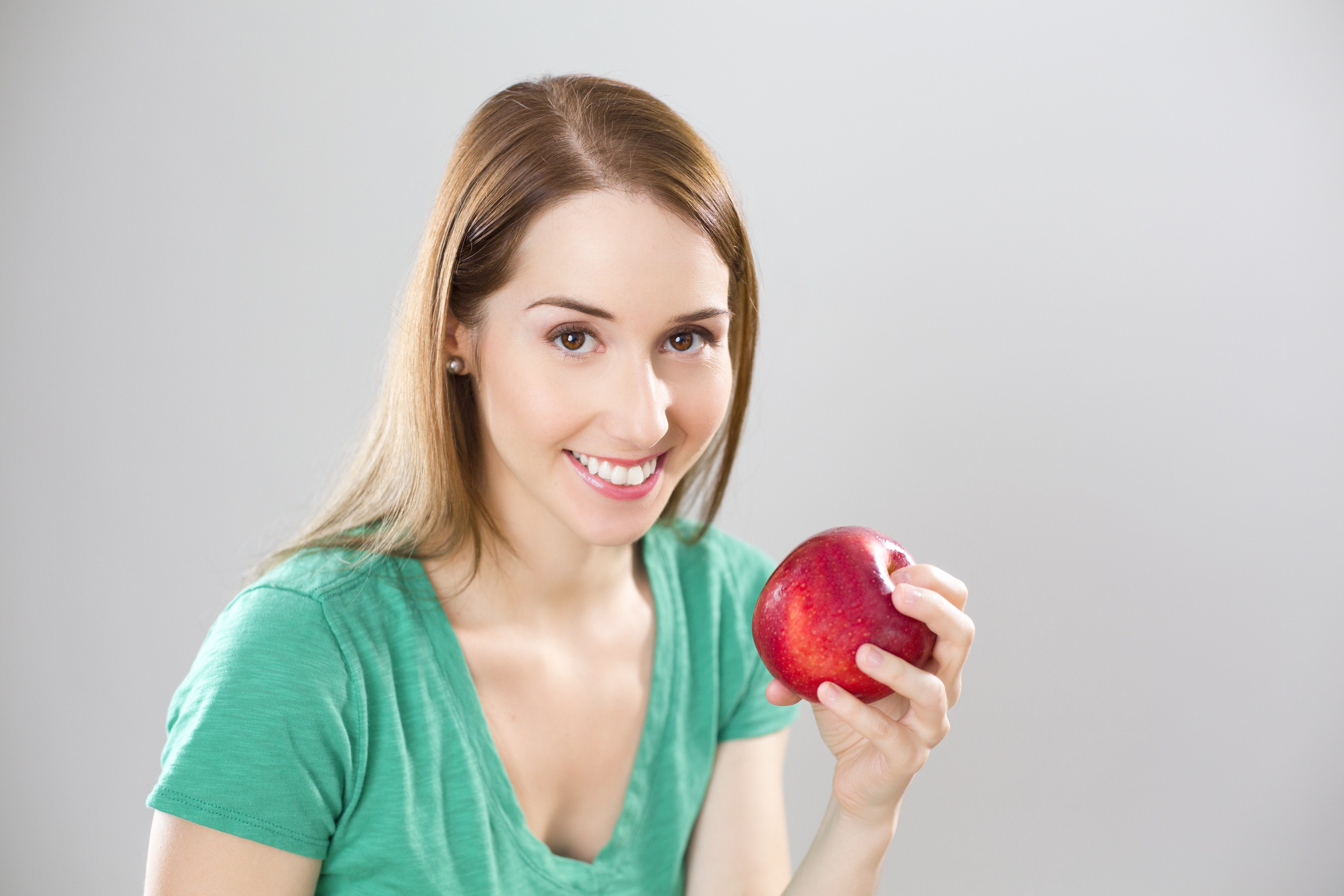 Portrait of young woman eating fruit against white background photo