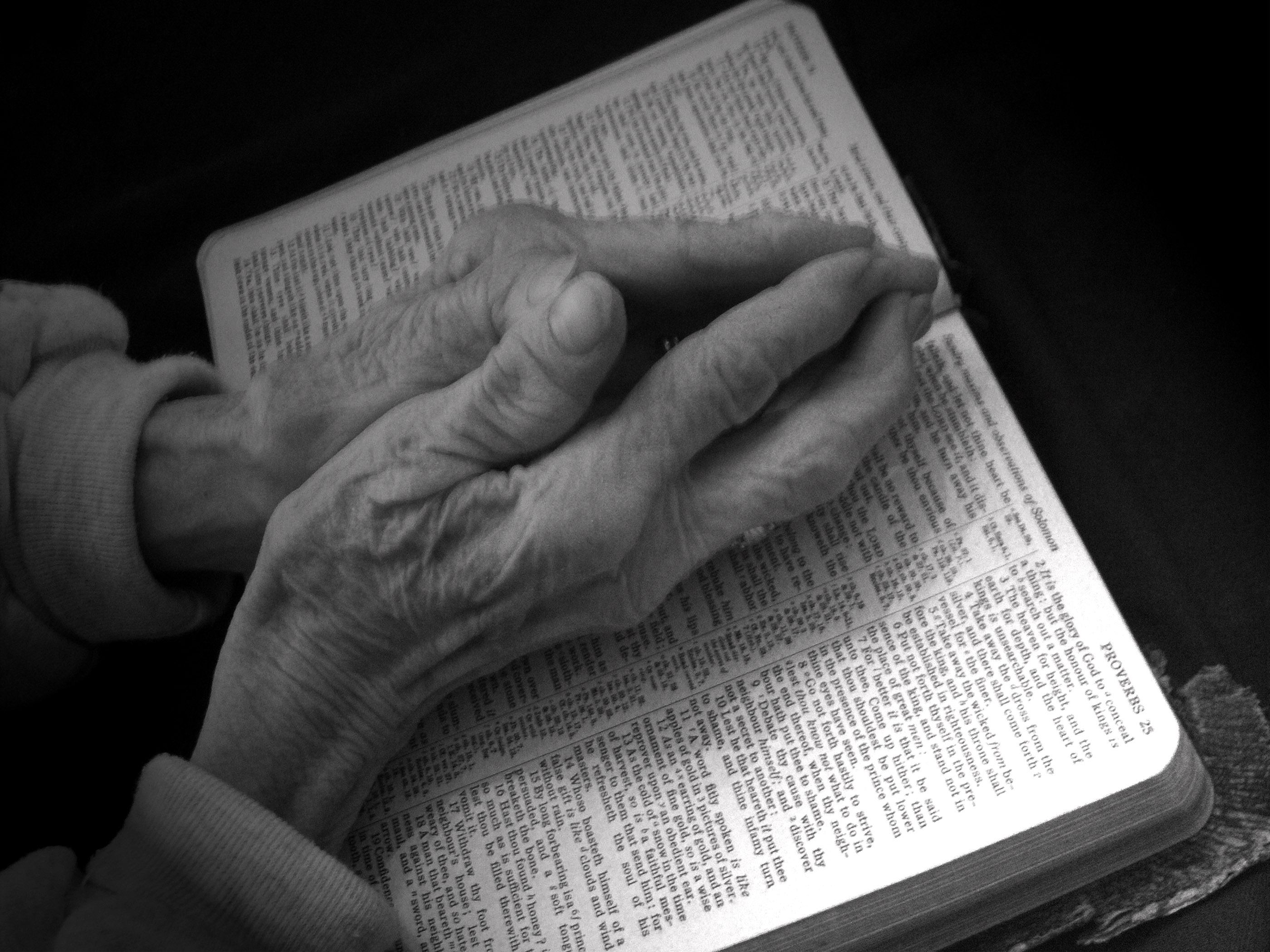 Praying hands on bible - black and white photo