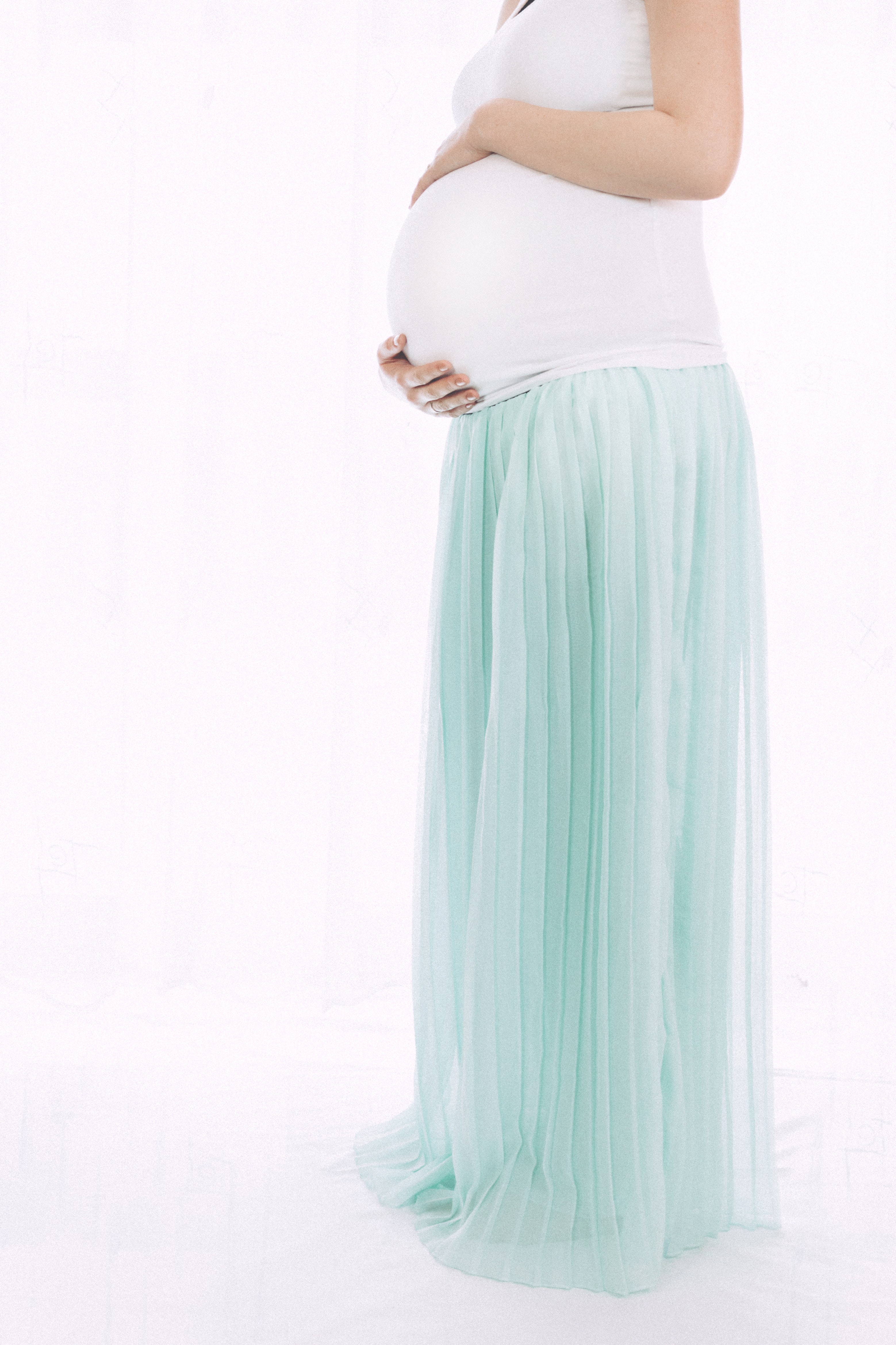 Pregnant woman standing in front of white wall photo